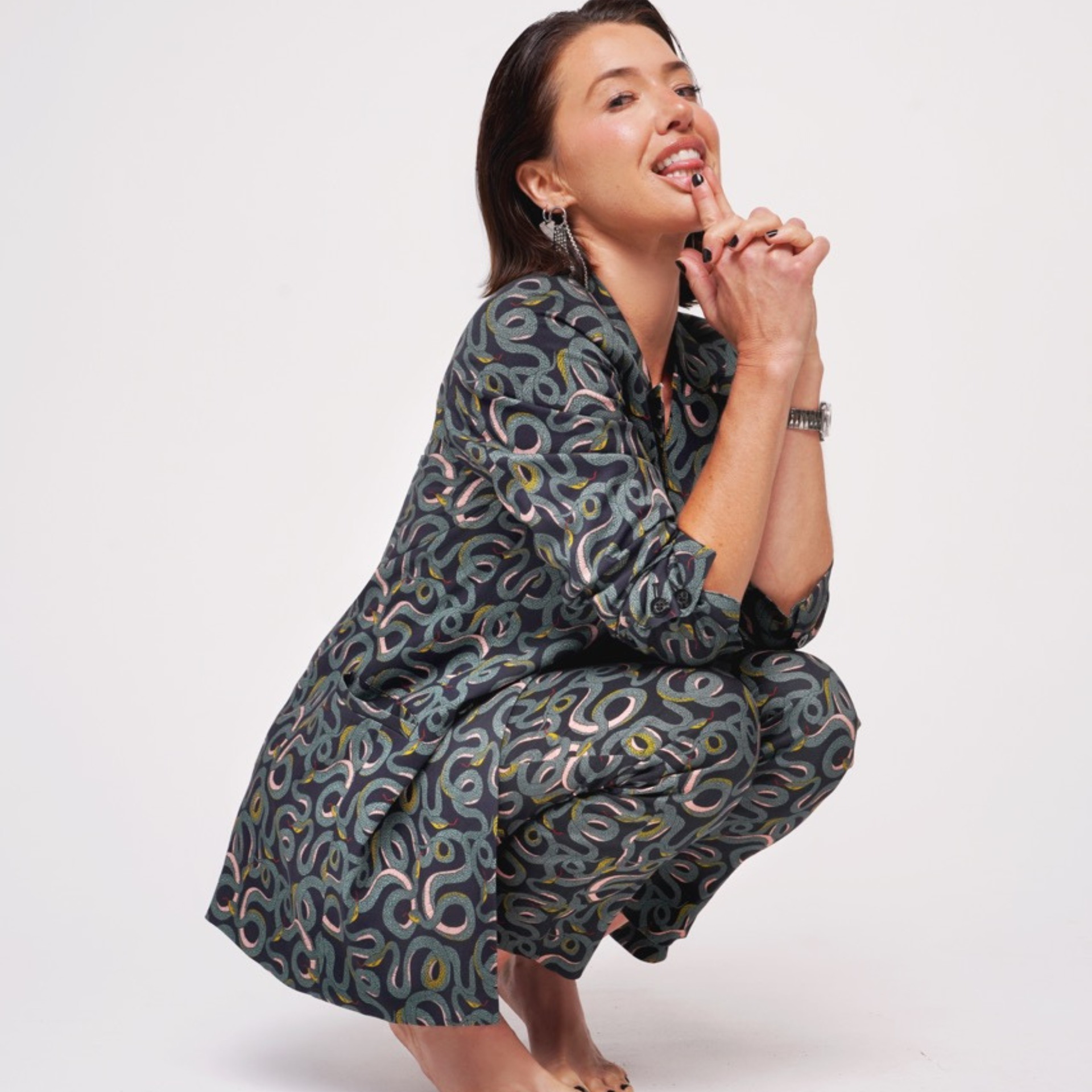 Against white background, Parvati Shallow is wearing the Serpentine Suit while crouching