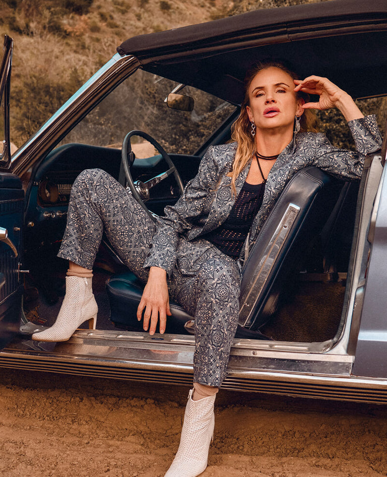 Juliette Lewis wears suit from the Juliette Lewis x Wildfang collab while sitting in drivers seat of vintage blue car with the door open.