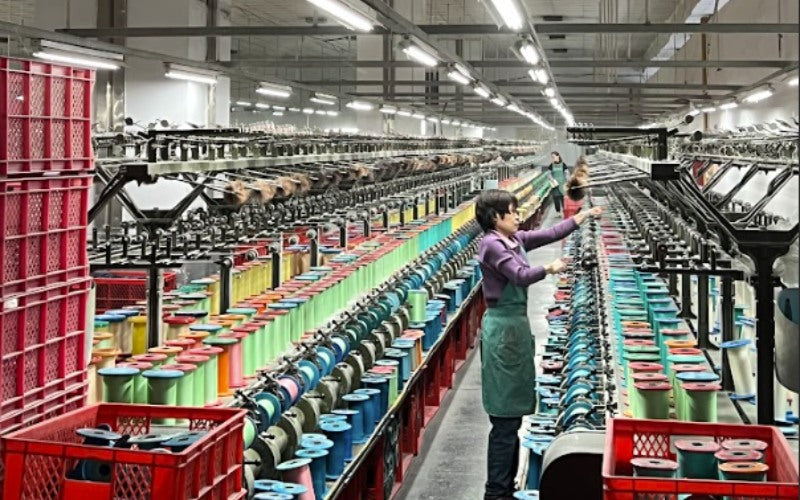 Image of manufacturing facility room showing machines with spools of thread