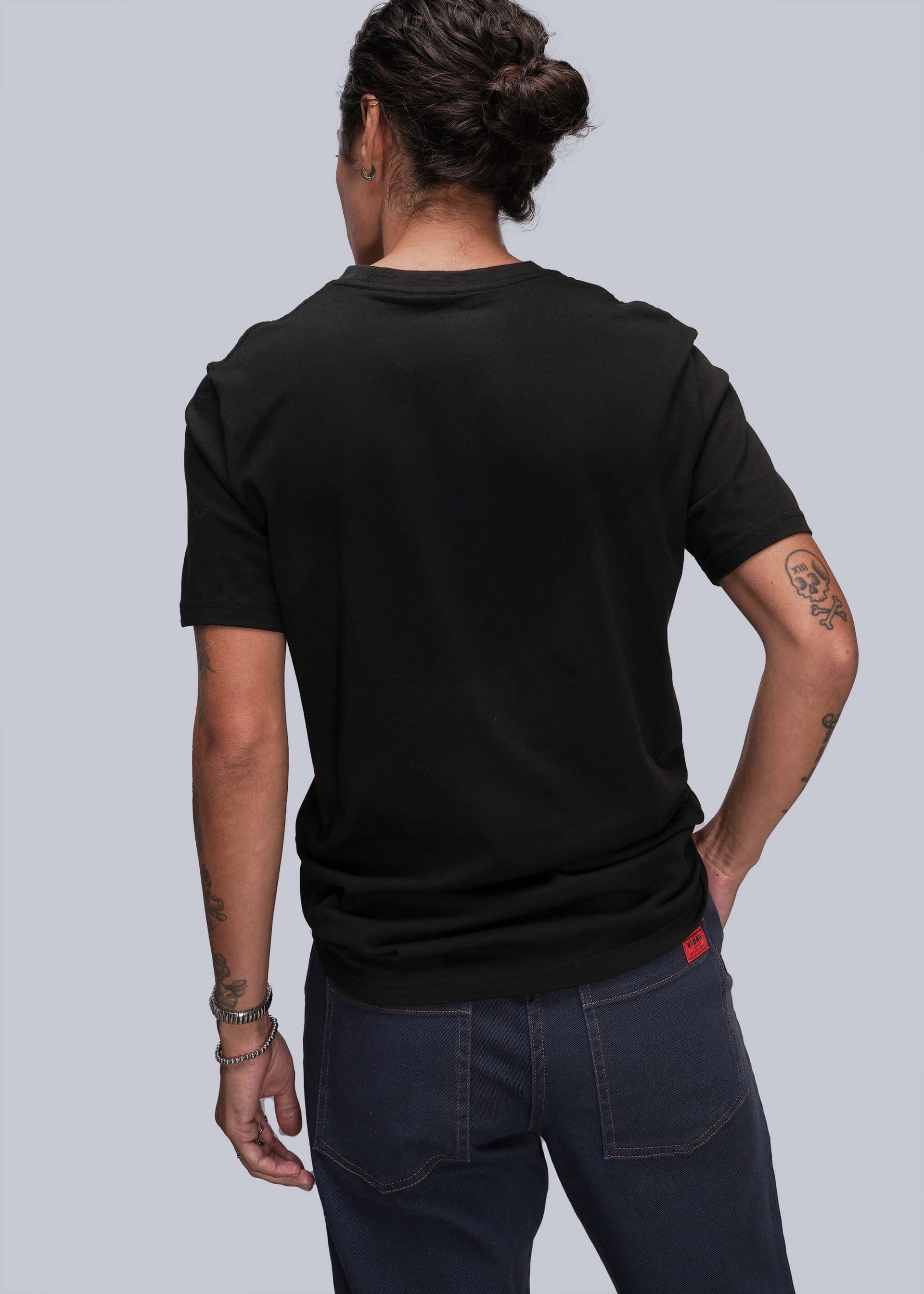 S=Person wearing a black t-shirt and dark jeans on a plain background