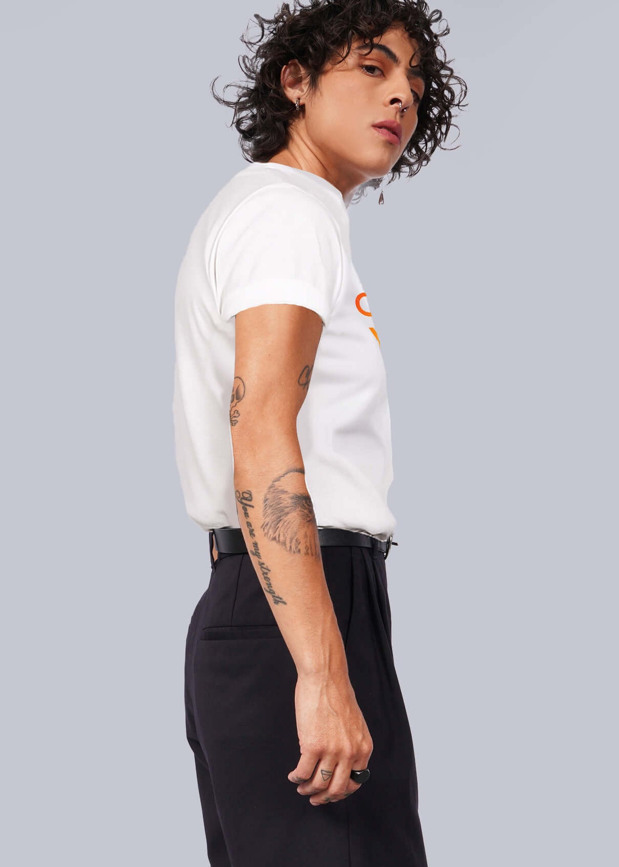 S=Person wearing a white t-shirt, black skirt, and black shoes against a plain background