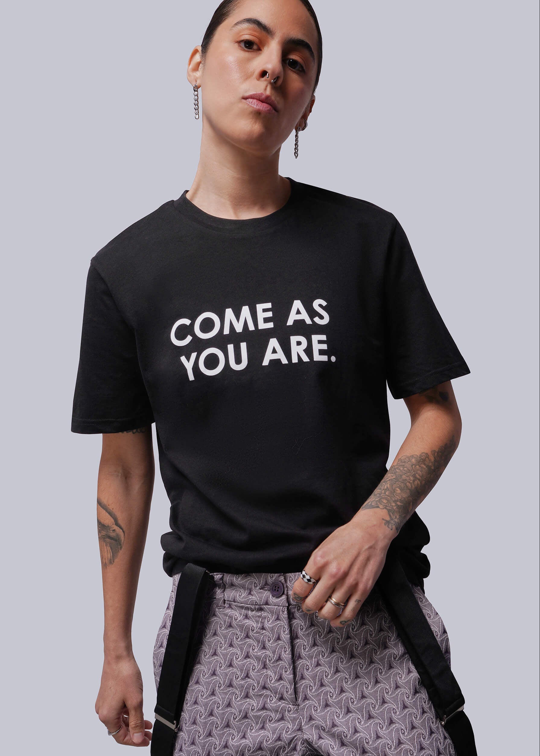 S=Person wearing a black t-shirt with 'COME AS YOU ARE.' text on a plain background