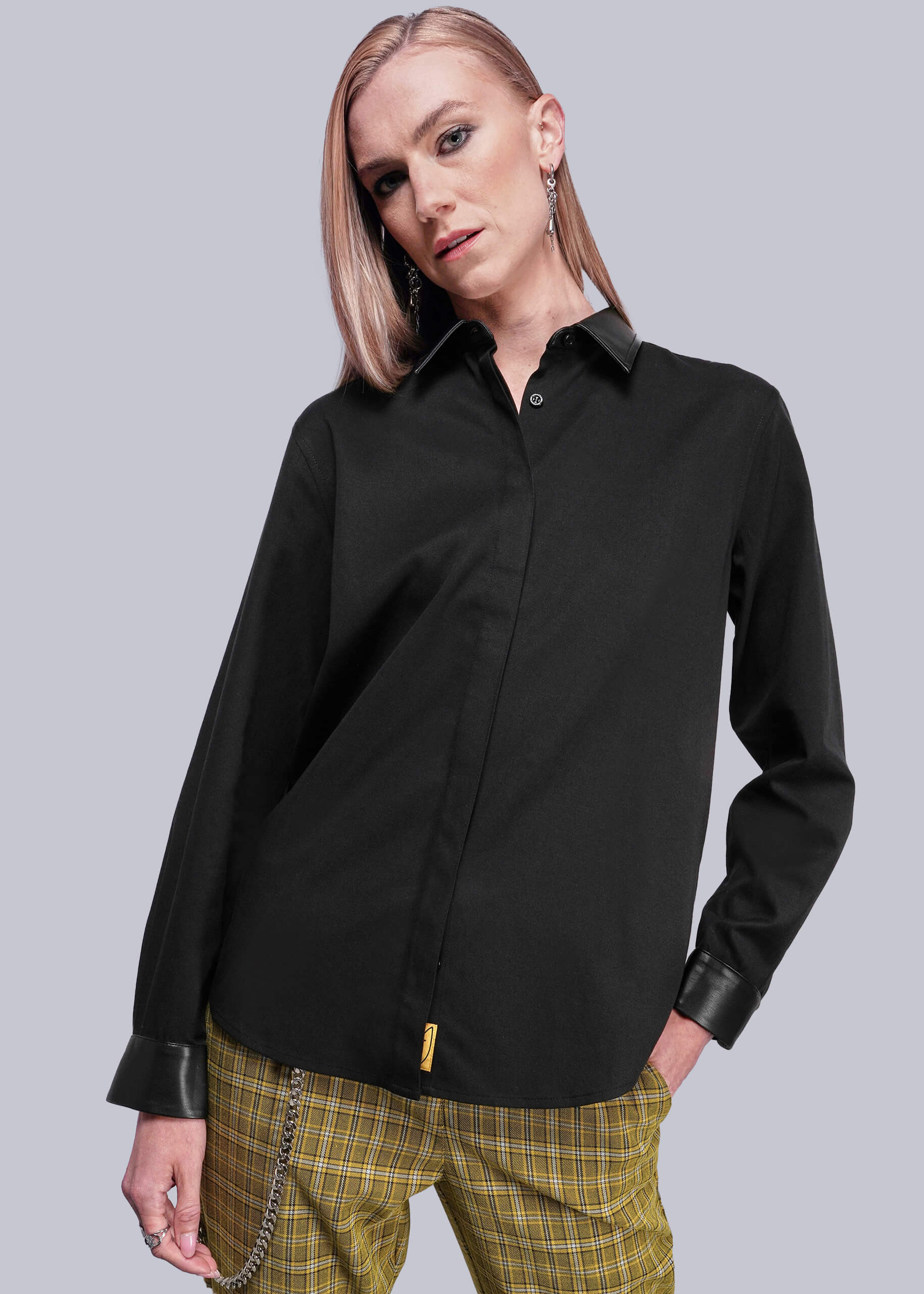 S=Person wearing a black shirt with vegan leather collar and cuffs on a gray background