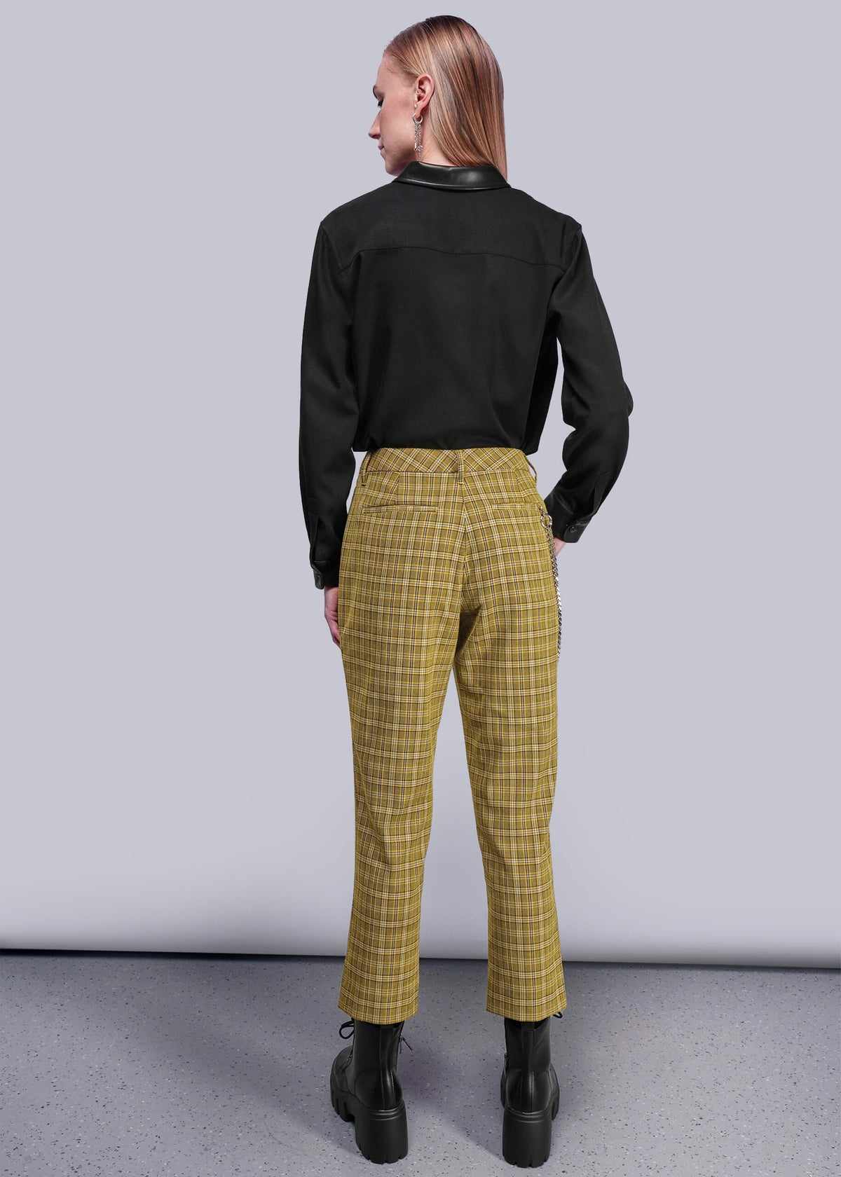 S=Back view of person wearing a black shirt and yellow plaid pants against a plain background