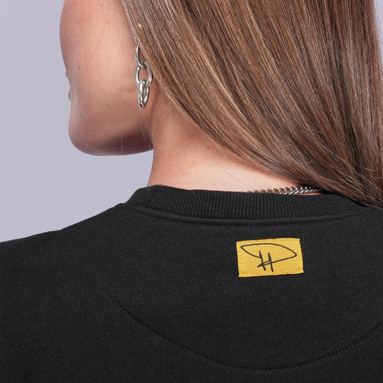 Black sweatshirt with a yellow label on a plain background