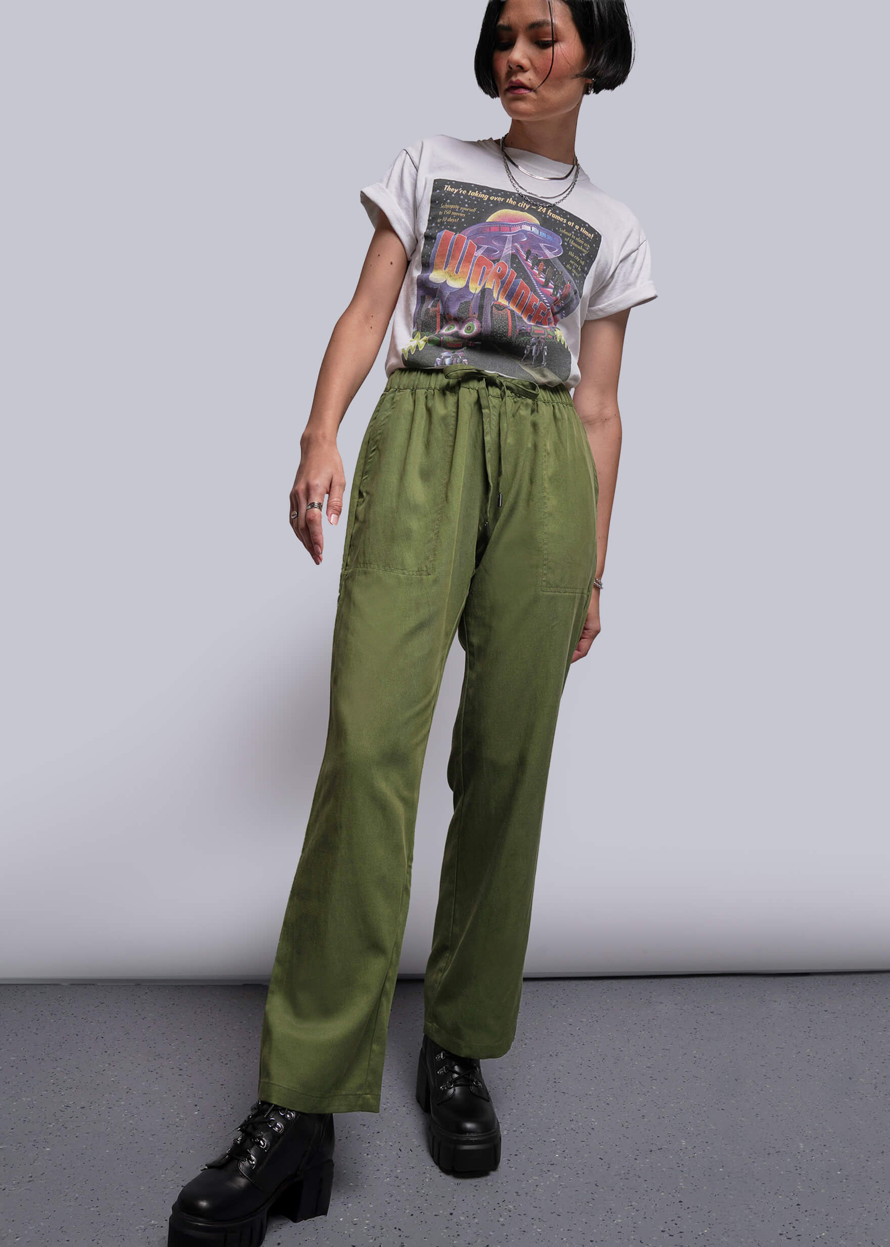 S=Person wearing a graphic t-shirt and green pants against a plain background