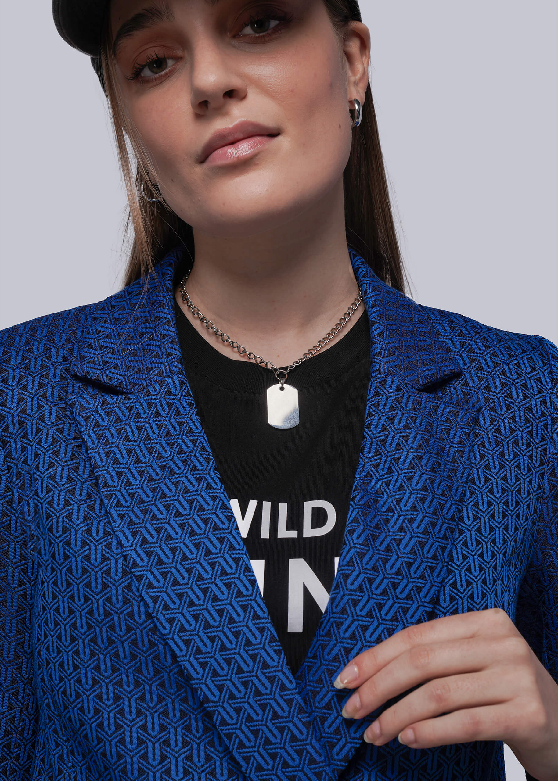 S=Person wearing a blue patterned blazer over a black shirt with visible text.