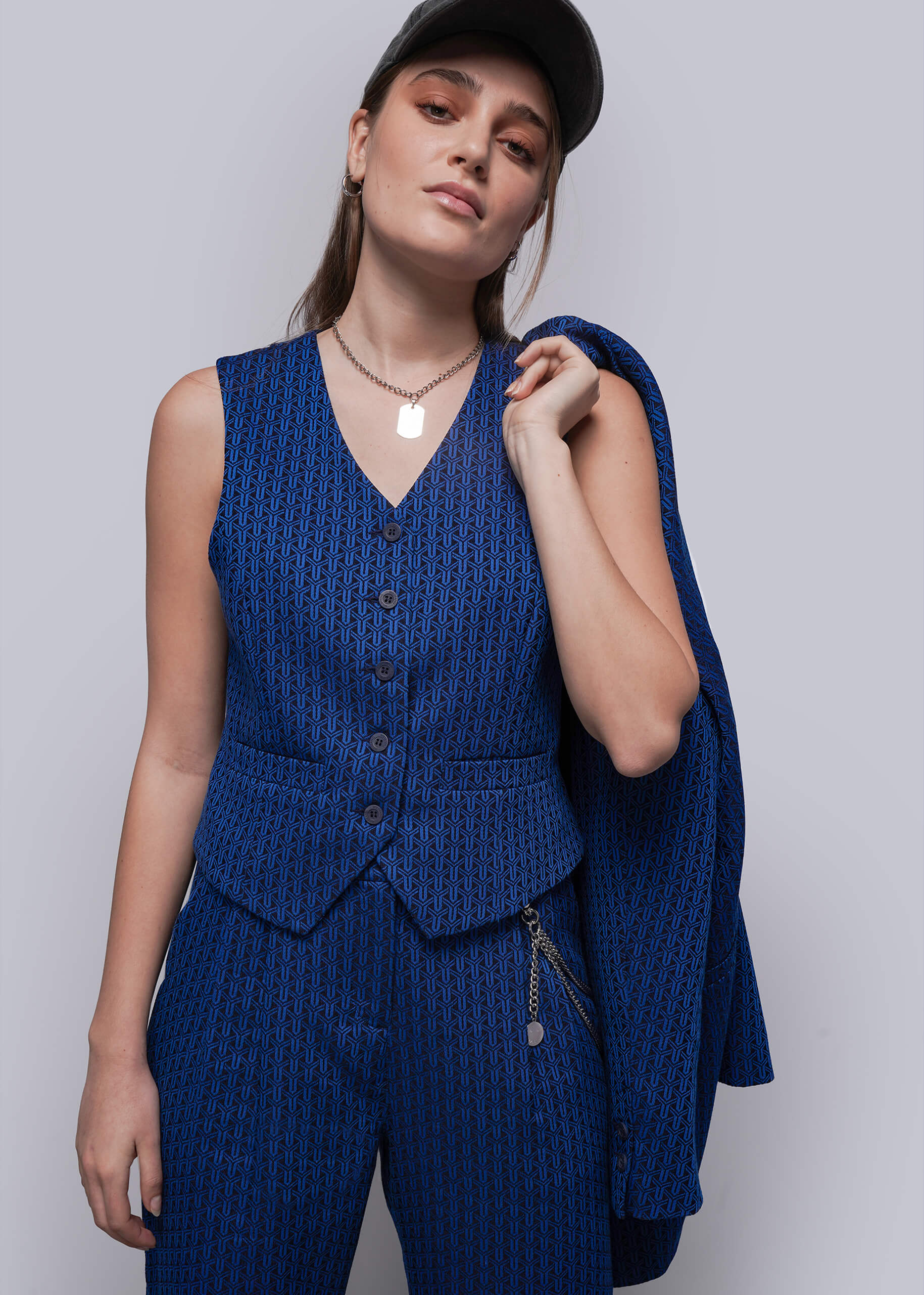 S=Woman wearing a blue patterned suit with a matching blazer against a plain background