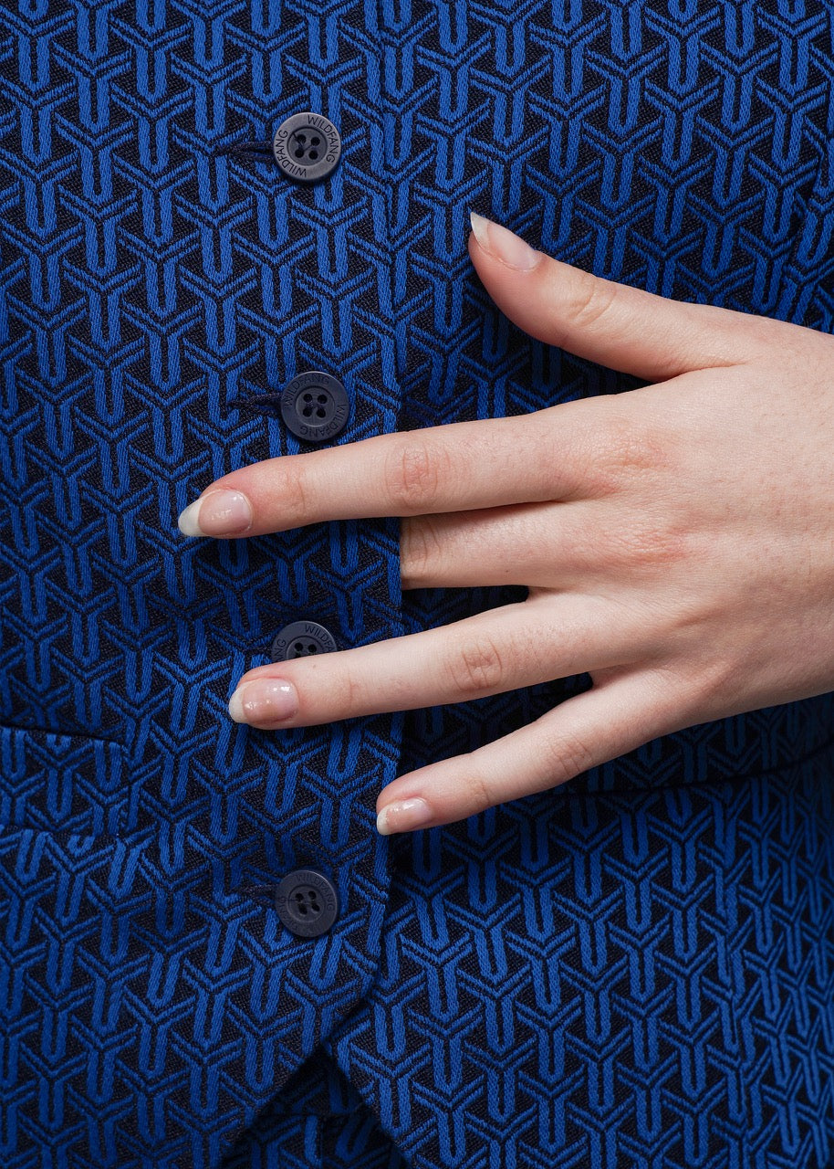 S=Hand touching a blue textured fabric with geometric pattern