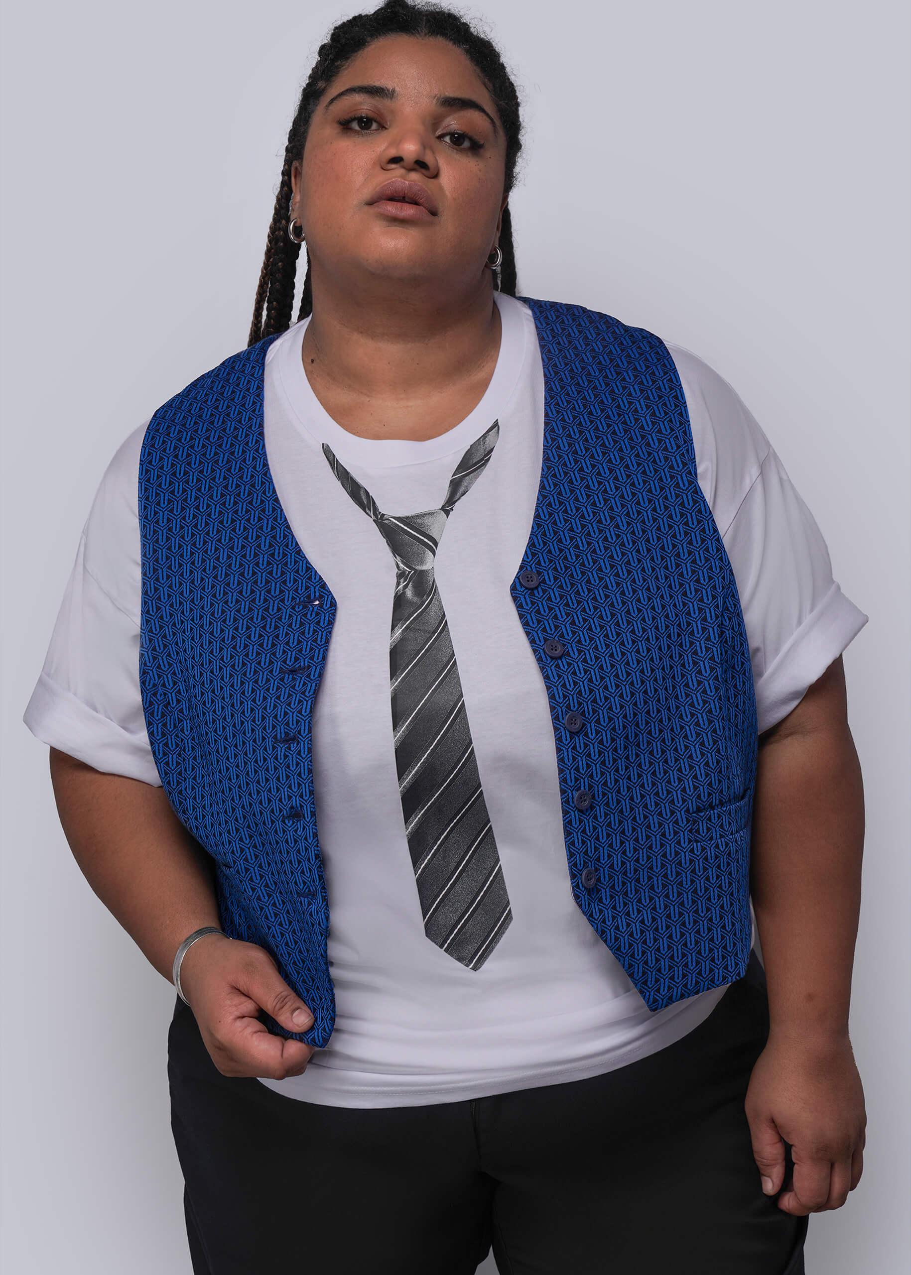 1X=Person wearing a blue vest over a white shirt with a tie design on a plain background