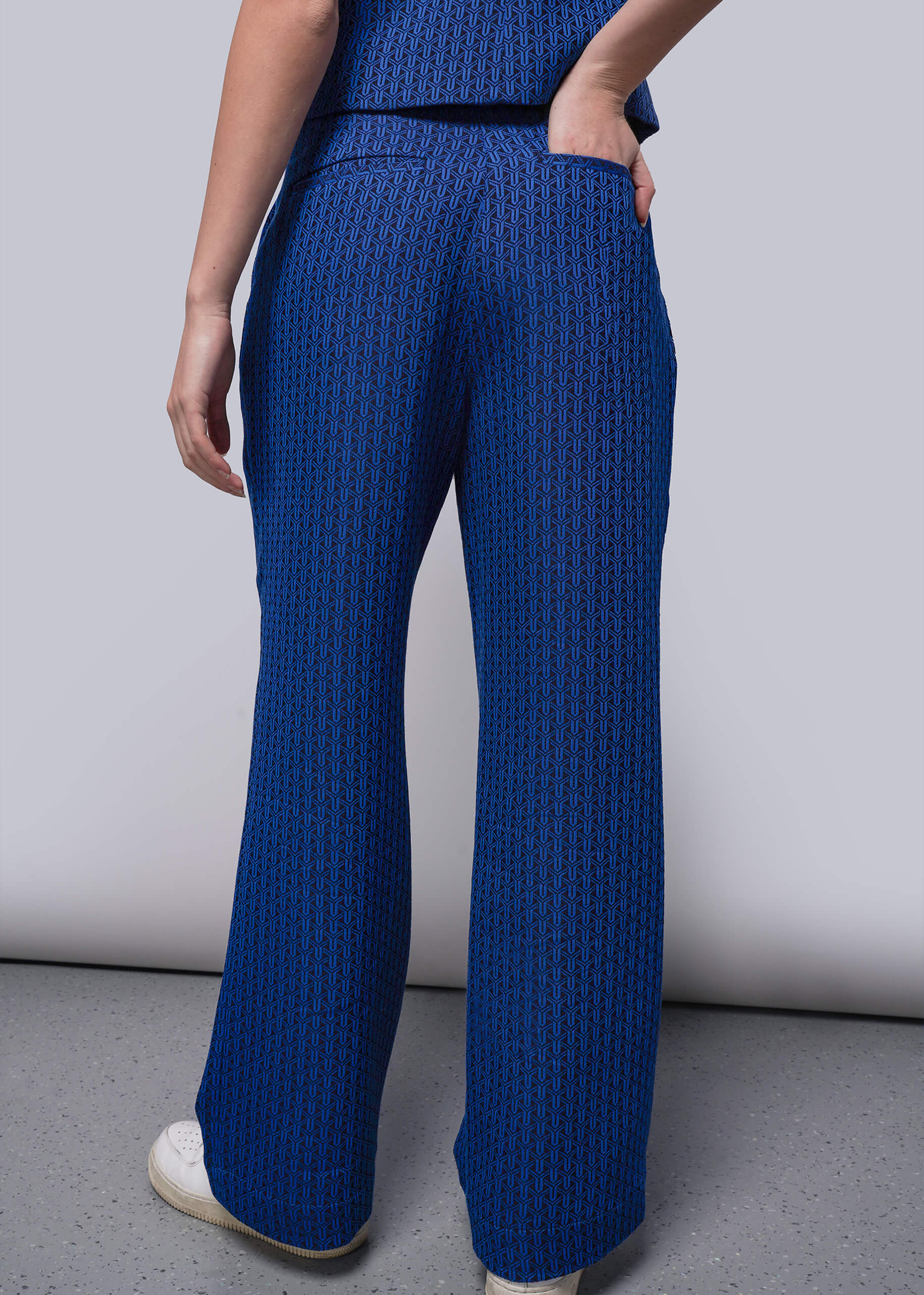 S=Person wearing blue textured pants against a plain background