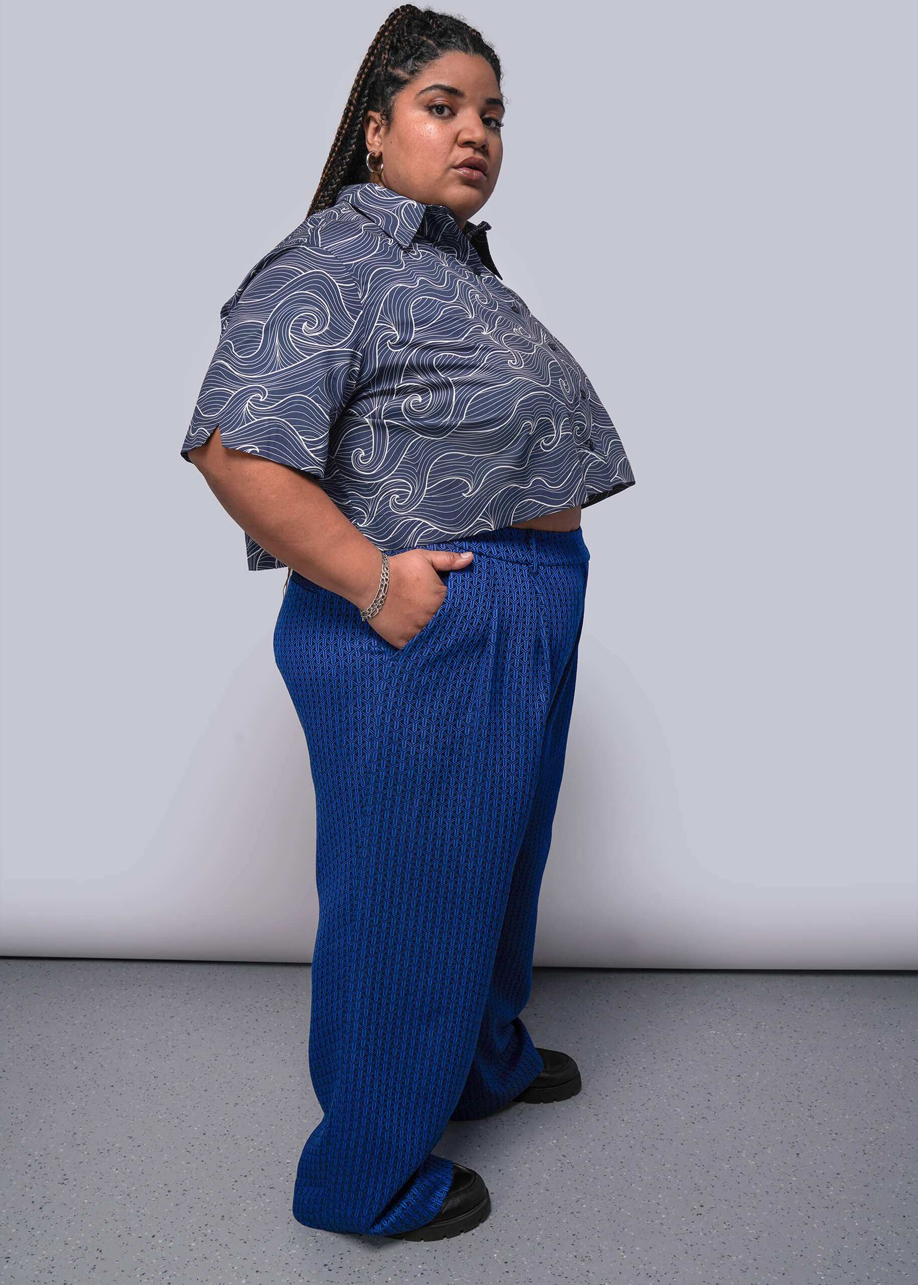 1X=Person wearing a blue patterned shirt and blue pants against a white background