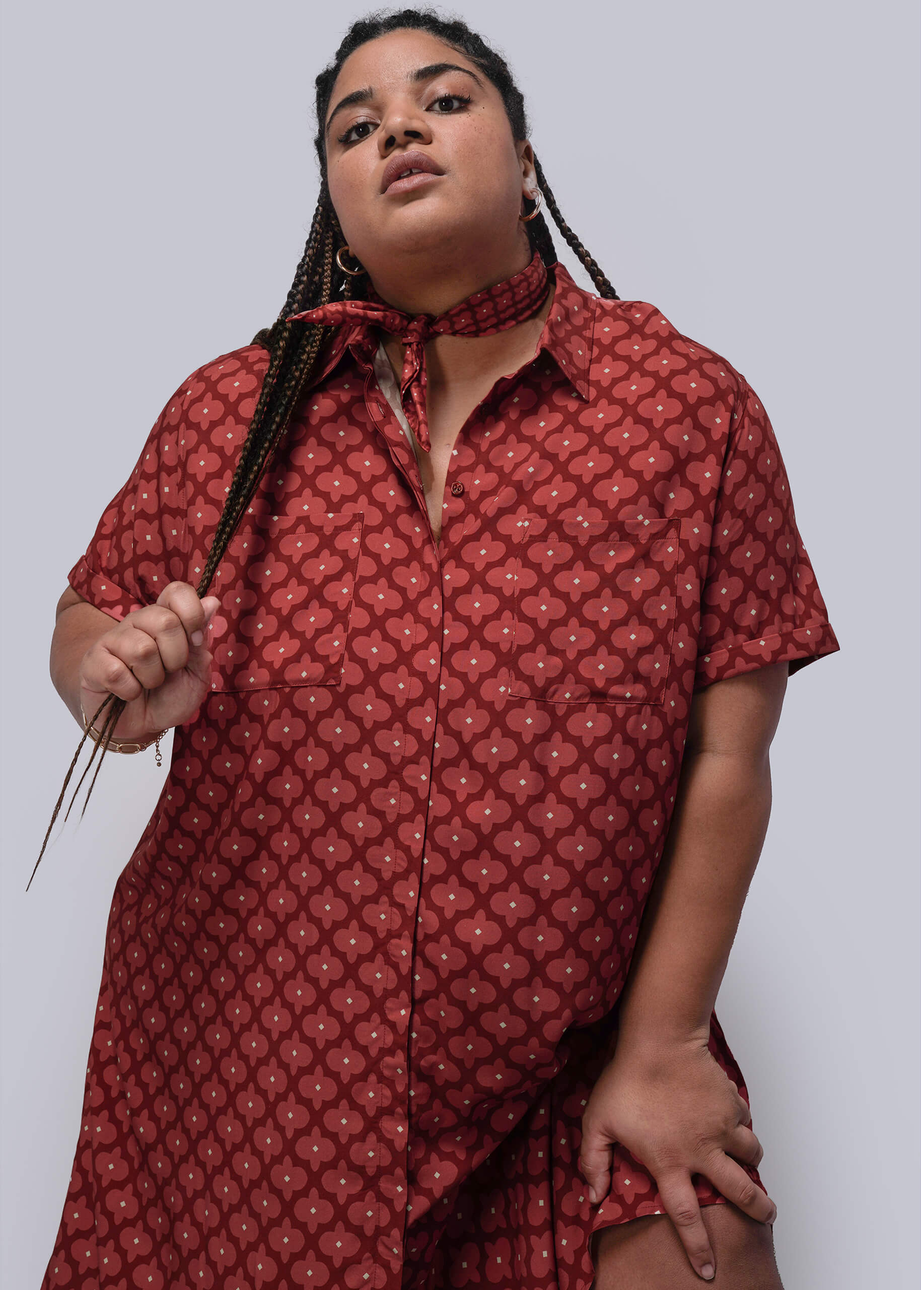 1X=Person wearing a red patterned dress and bandana against a plain background