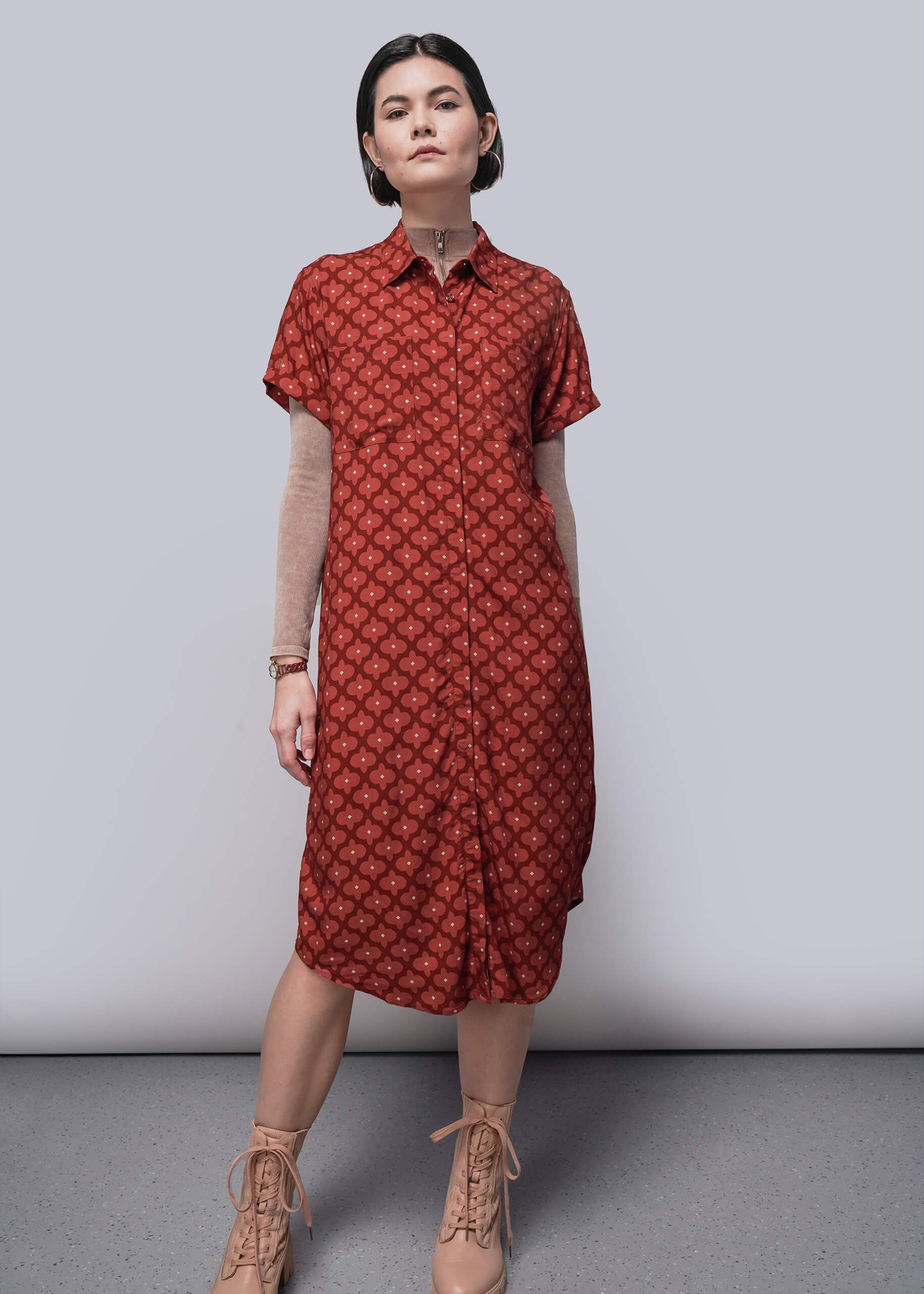 S=Woman wearing a red patterned dress against a plain background