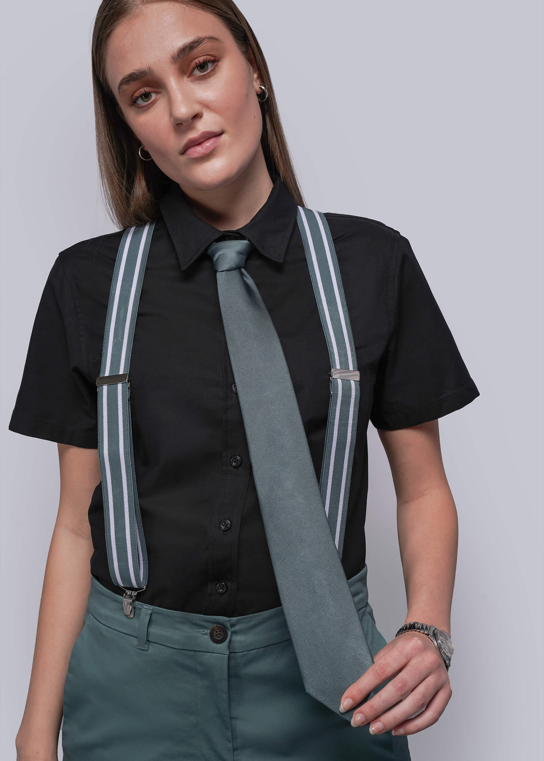 Person wearing a black shirt, blue tie, and suspenders on a plain background