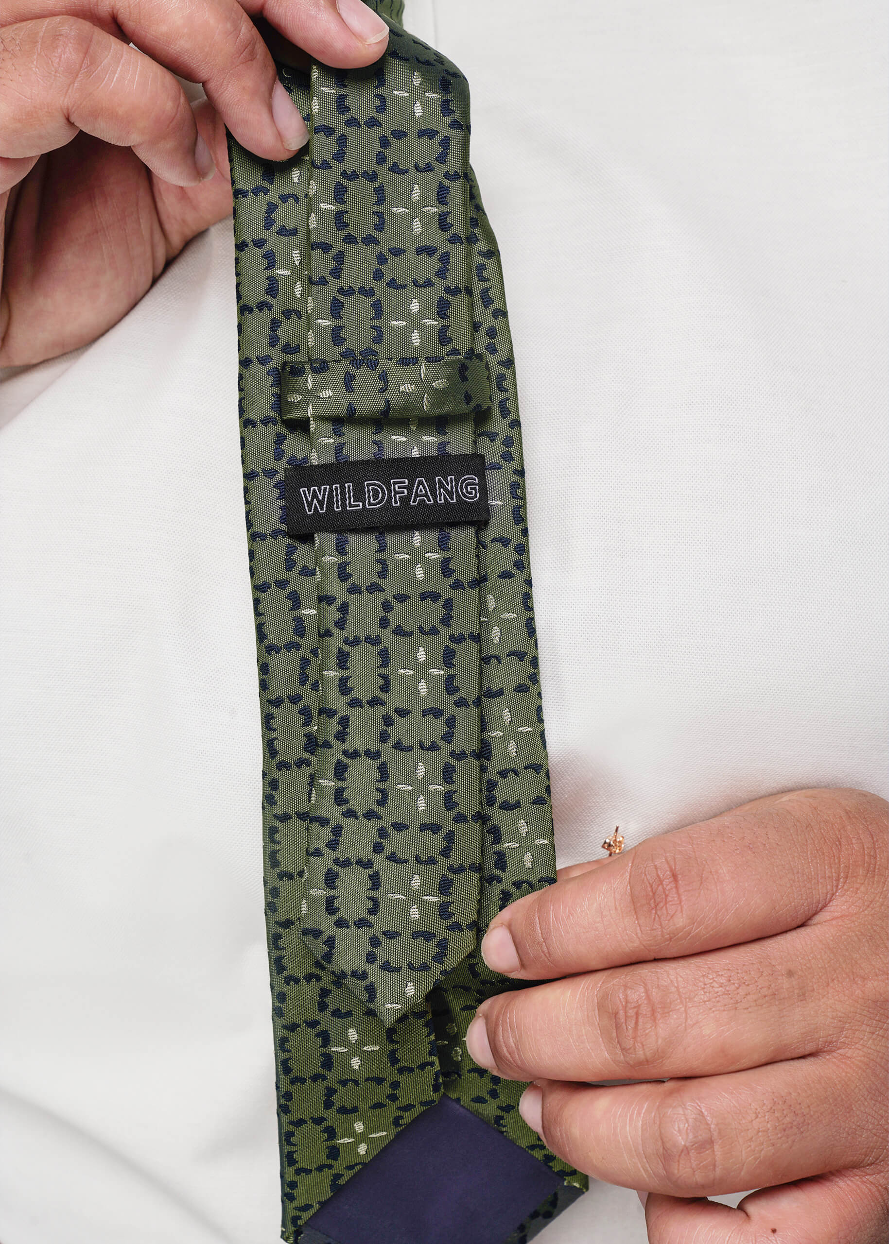 Gray patterned tie with 'WILDFANG' label held by a person against a white background