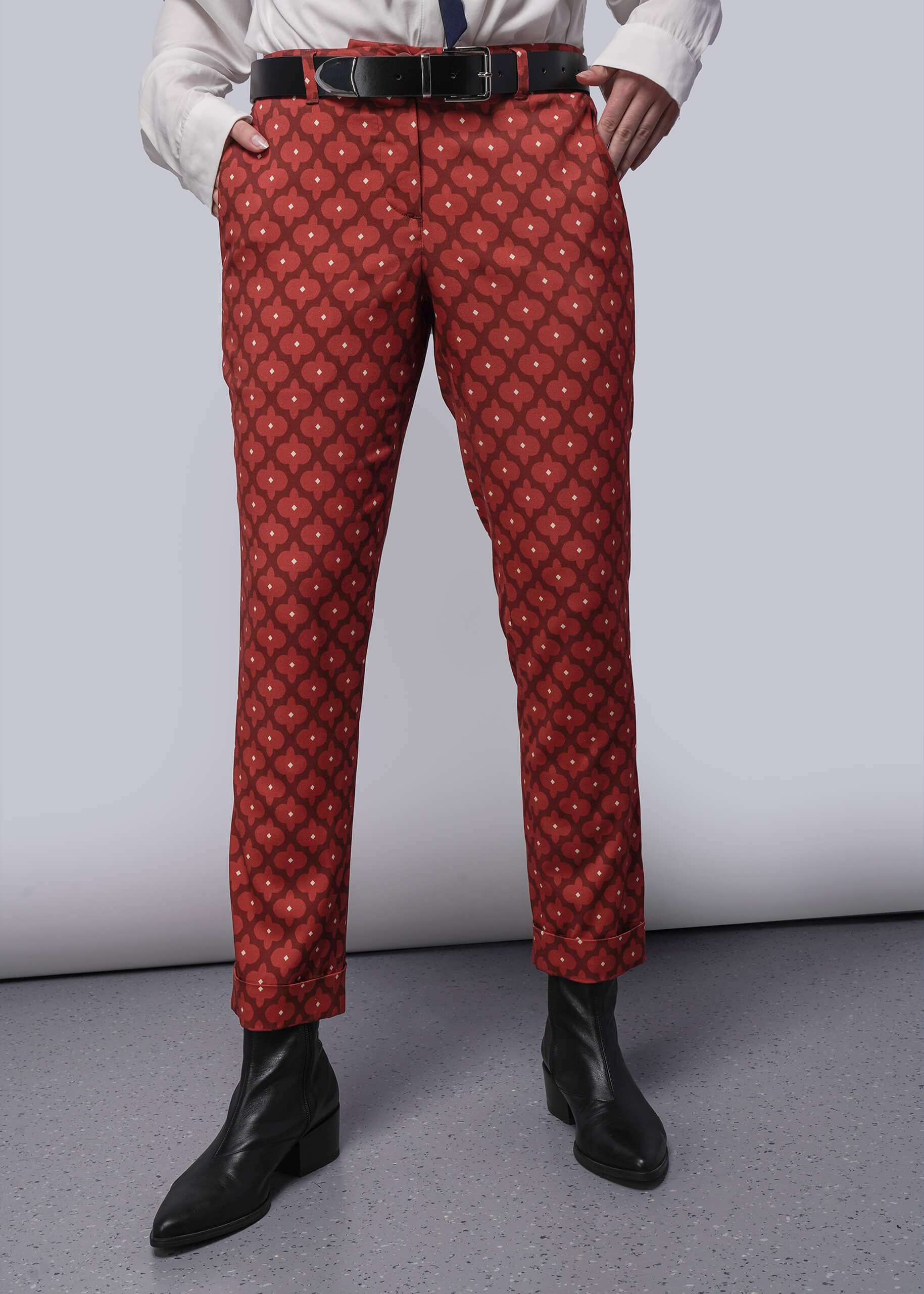S=Person wearing red patterned pants with a white shirt and black shoes on a gray background