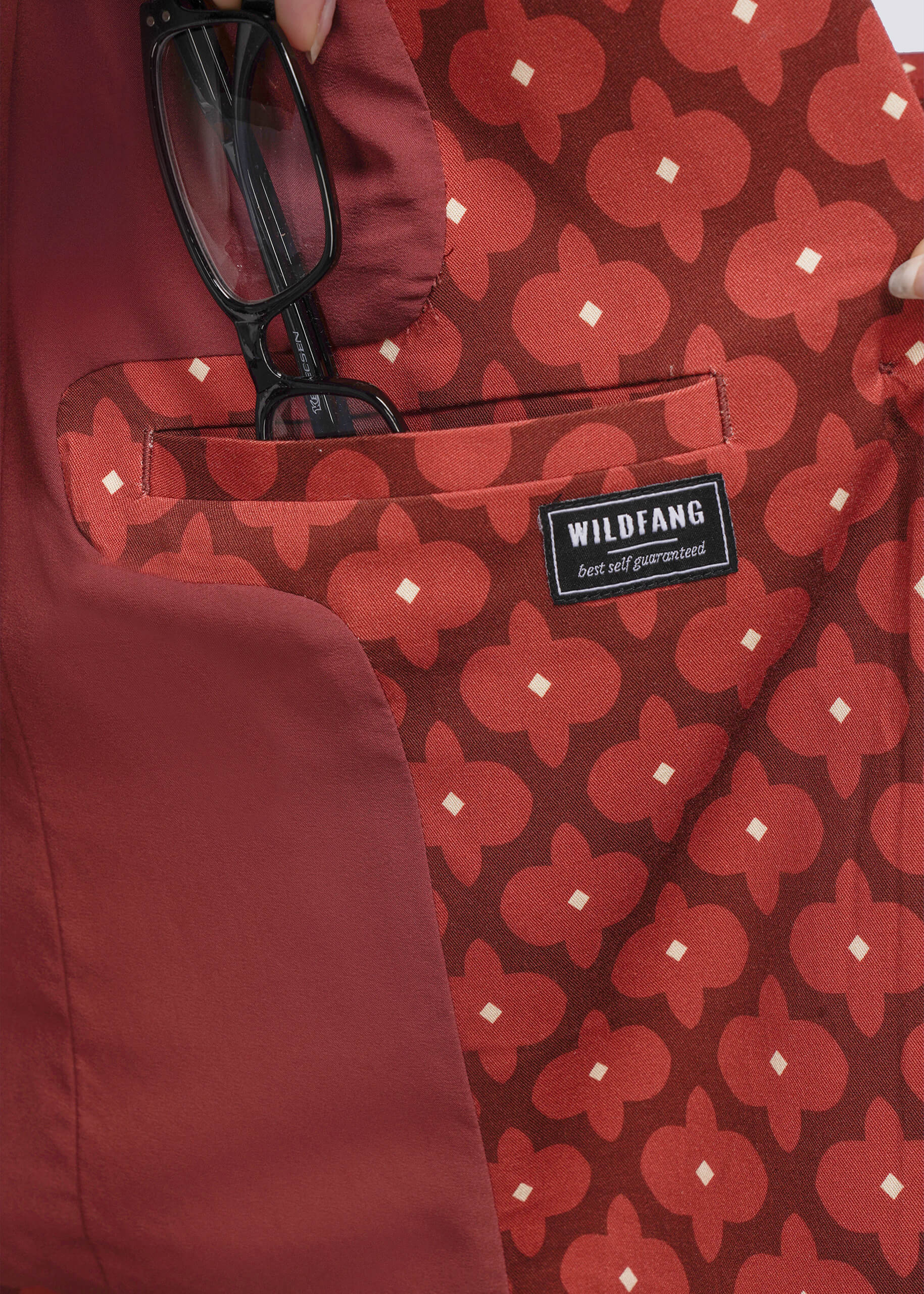 S=Close up of red patterned blazer interior pocket with a 'Wildfang' label 