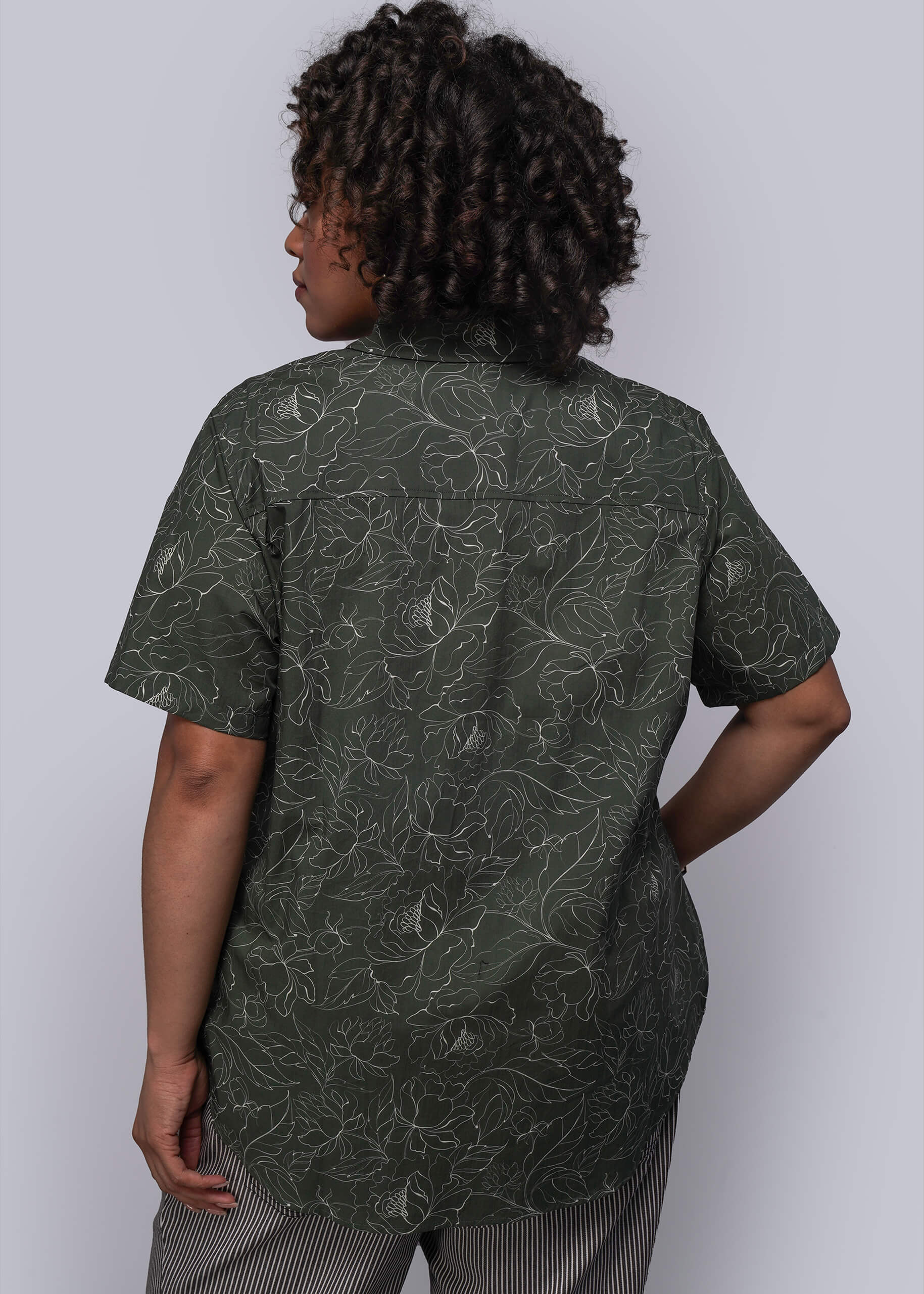 1X=Person wearing a green patterned shirt against a white background