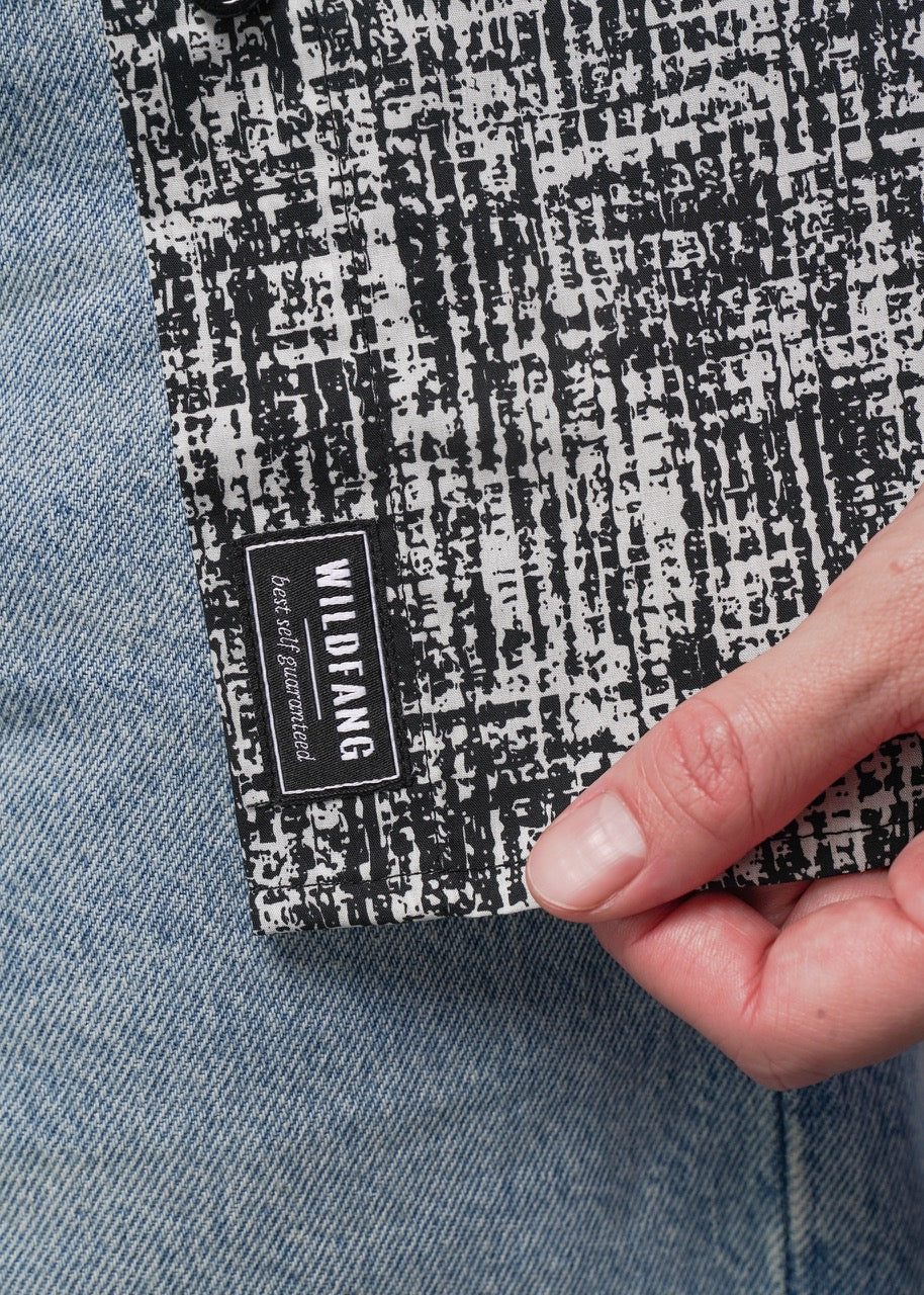 Close-up of a hand holding a black and white patterned fabric with 'Wildfang' branding.