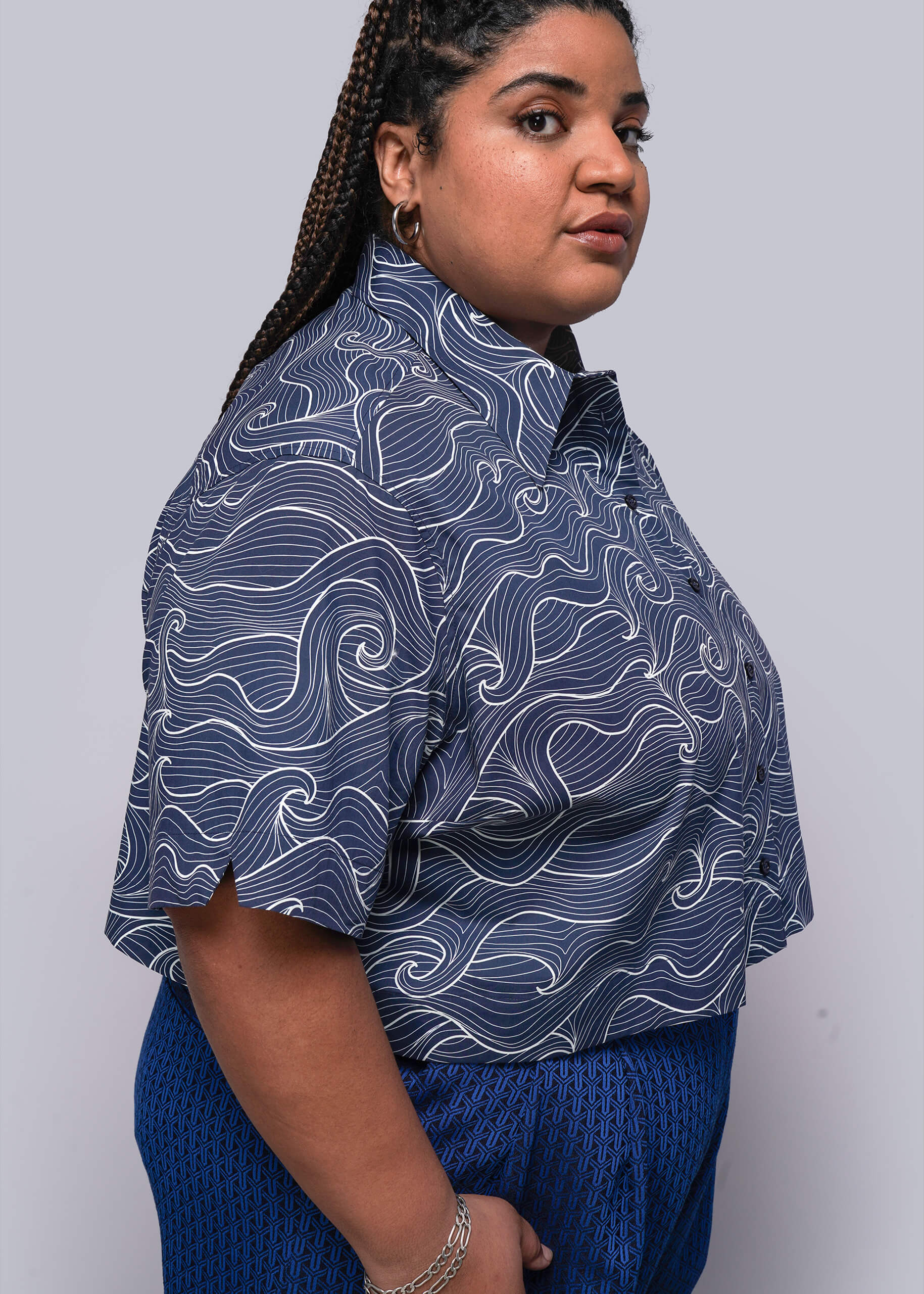 1X=Person wearing a blue patterned top and blue pants against a plain background