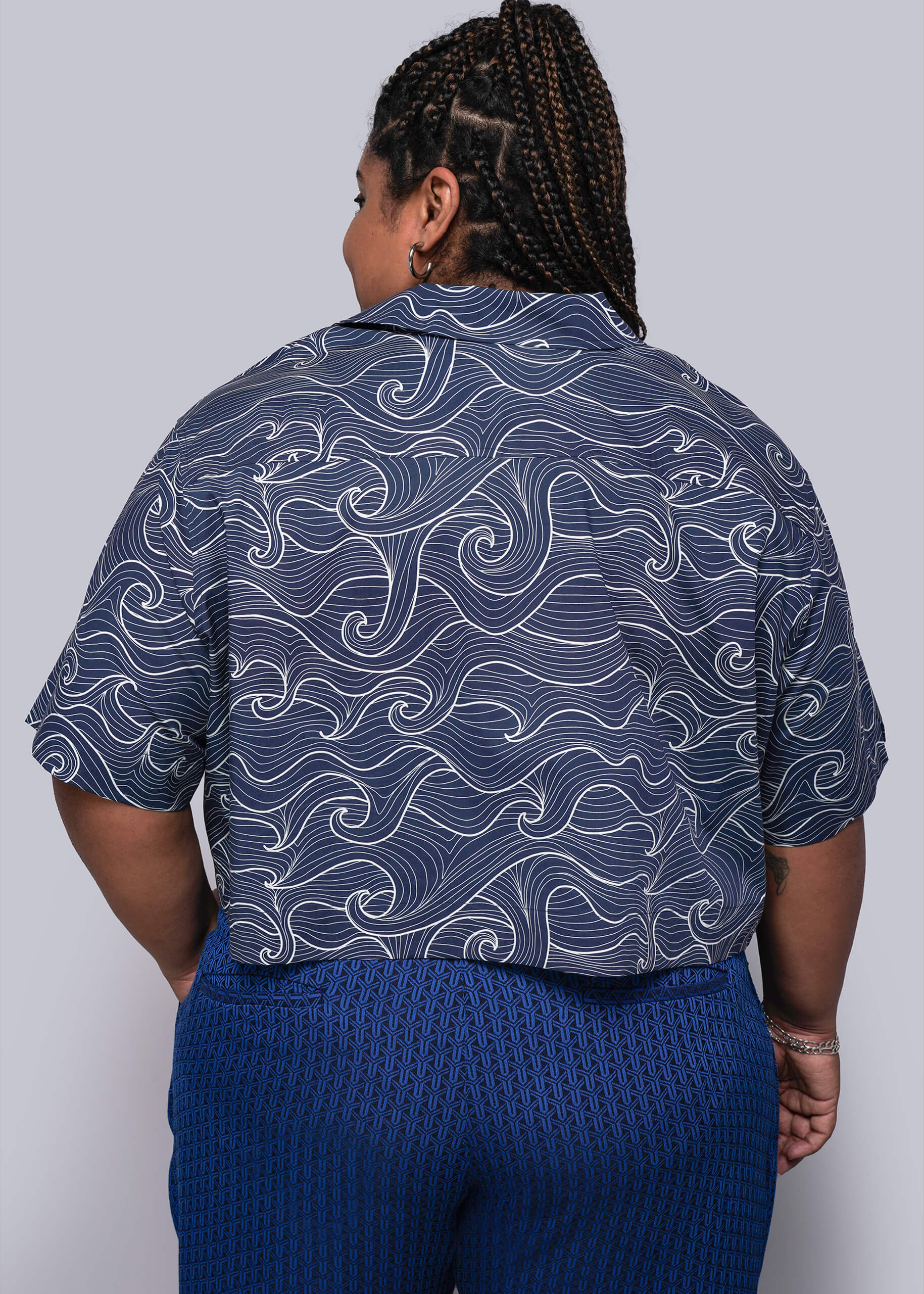1X=Person wearing a blue patterned shirt and blue pants on a plain background