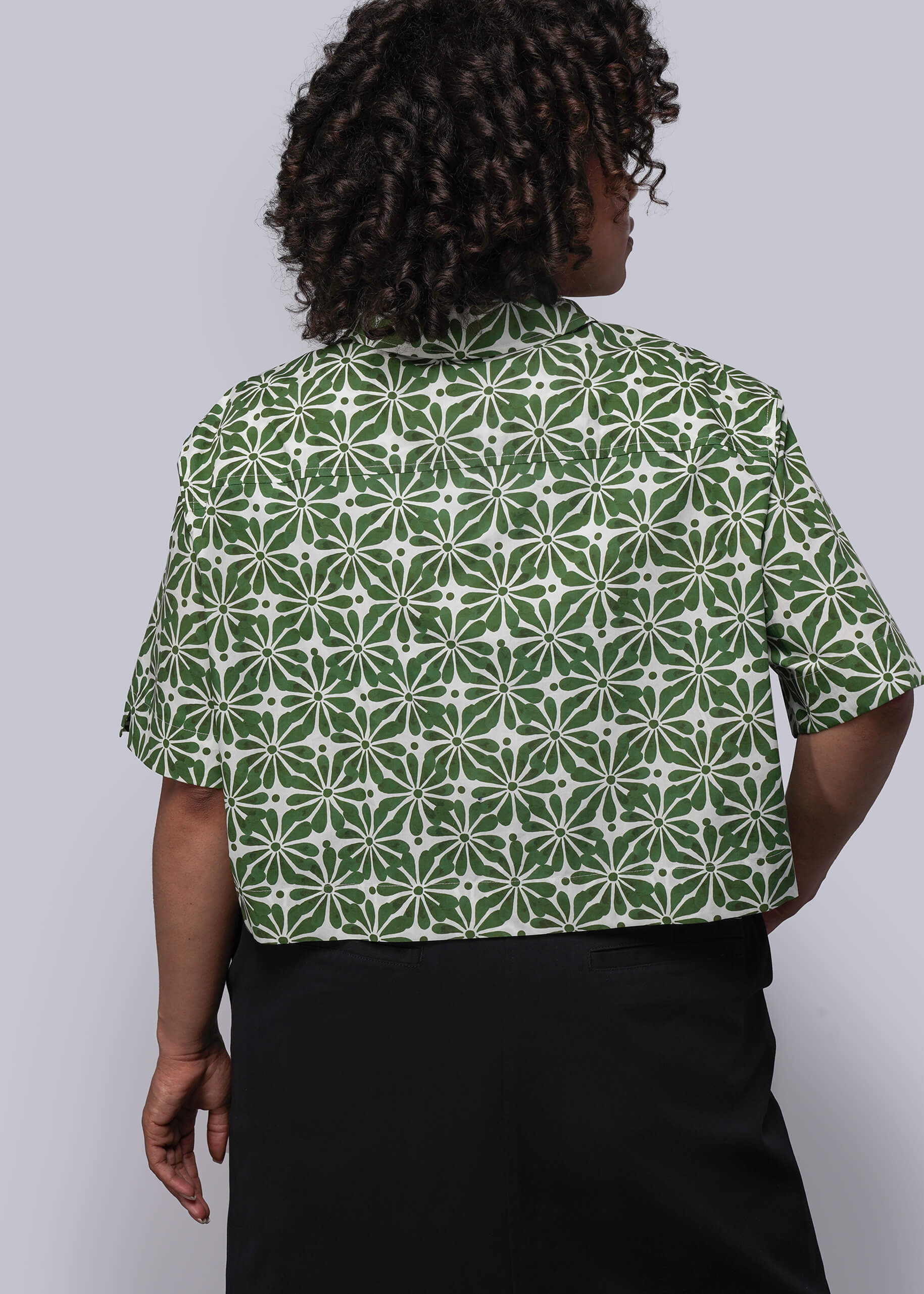 1X=Person wearing a green and white patterned shirt against a plain background