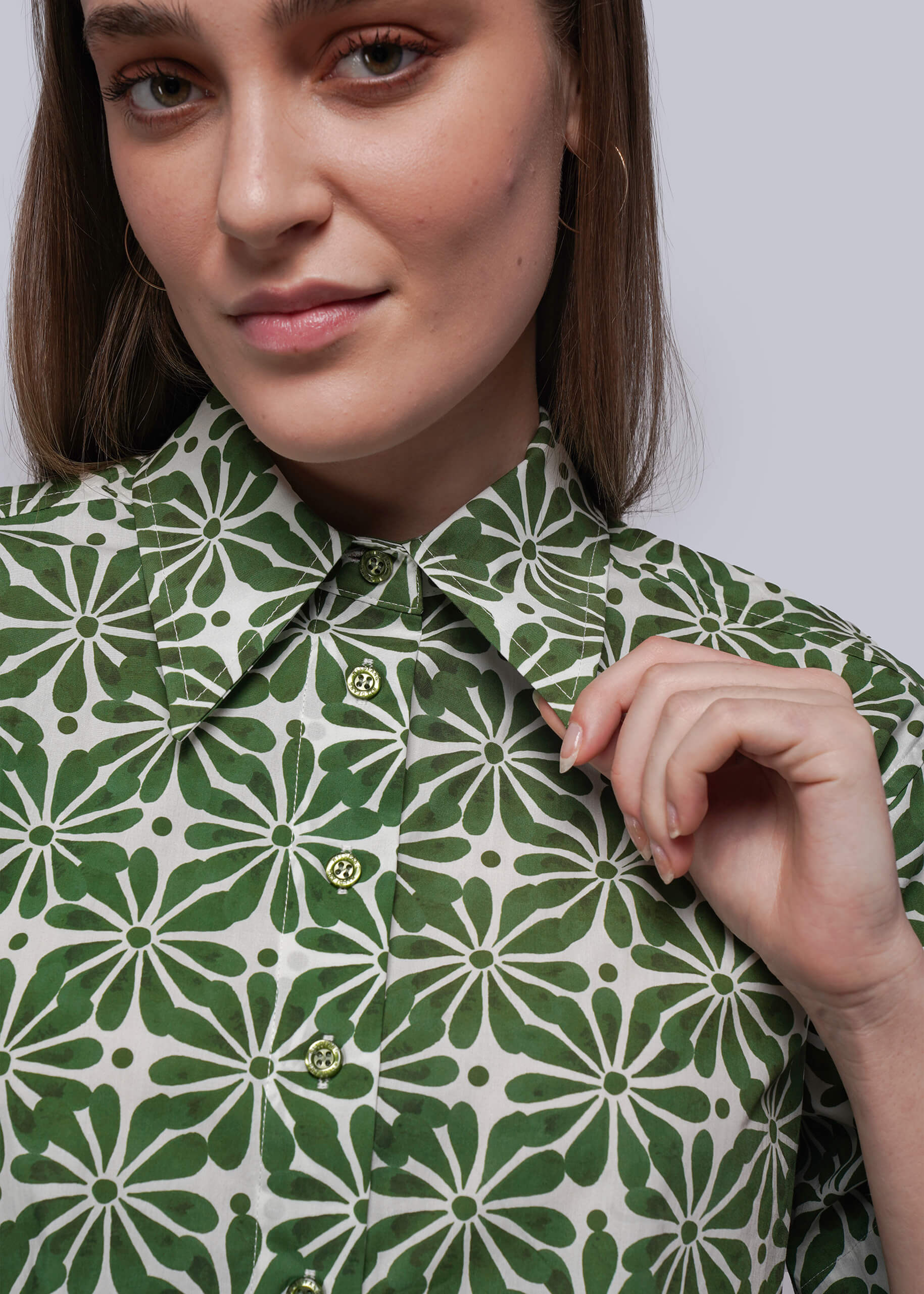Woman wearing a green and white patterned shirt against a plain background