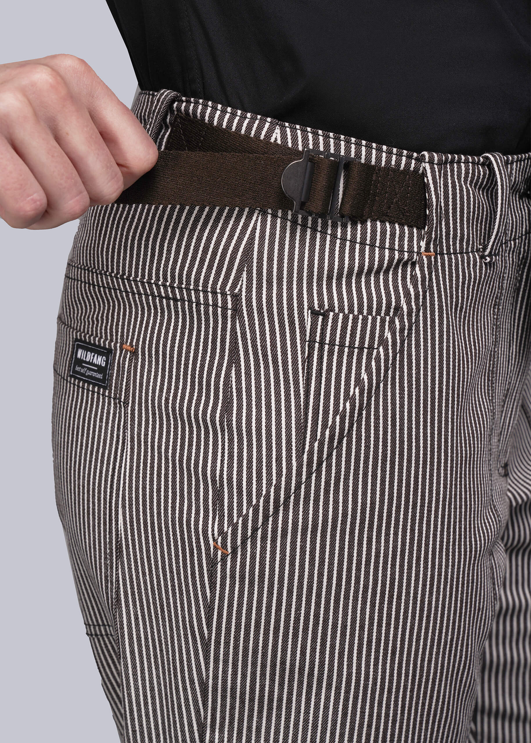 Close-up of striped pants with an adjustable waist buckle and visible brand label on a light gray background
