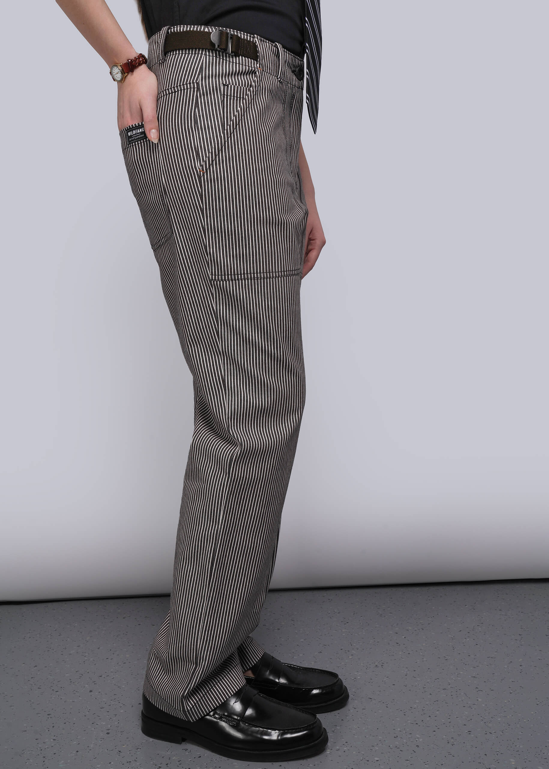 S=Person wearing brown and white stripe pants and black shoes on a plain background