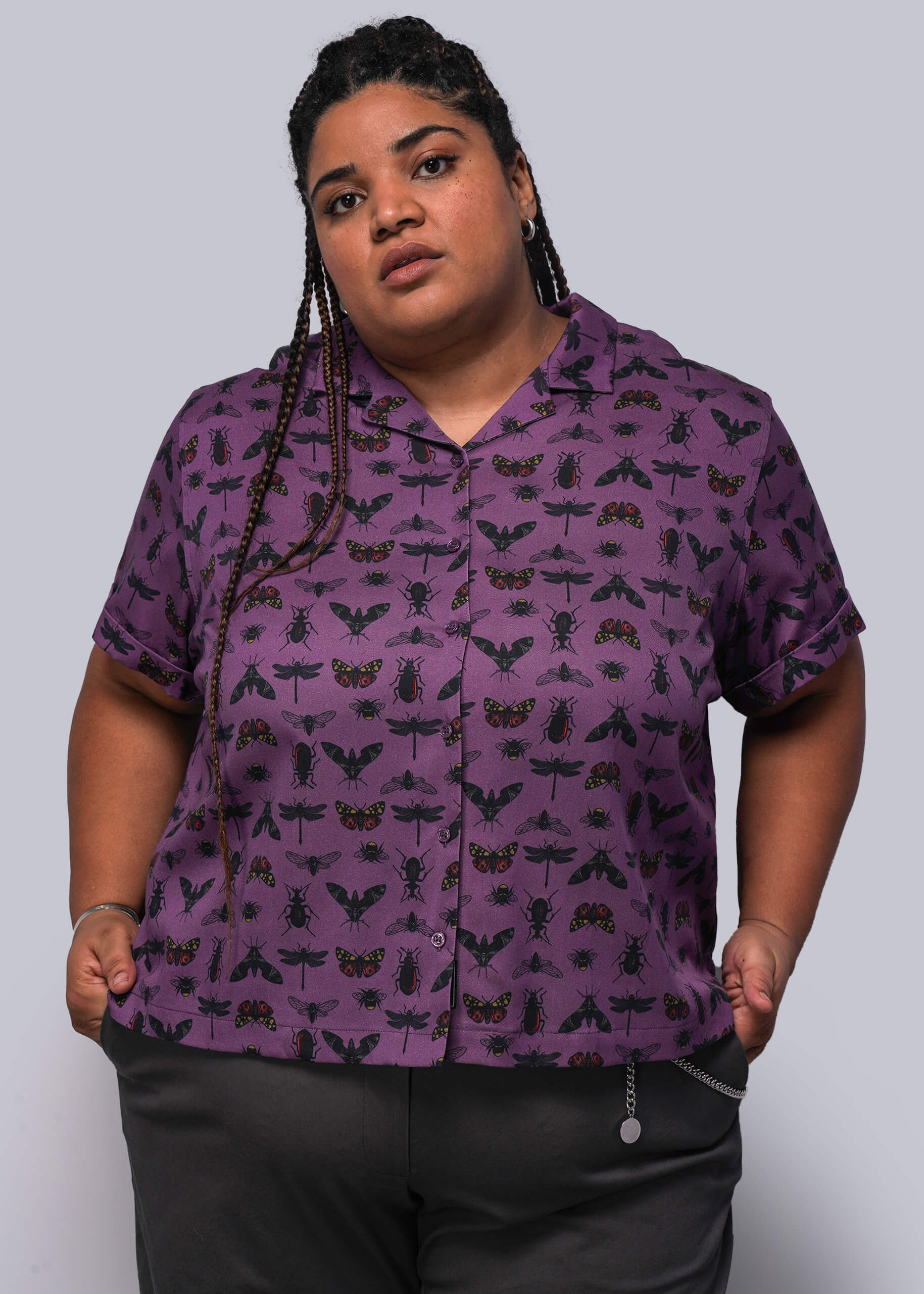 1X=Person wearing a purple shirt with black insect pattern on a plain background