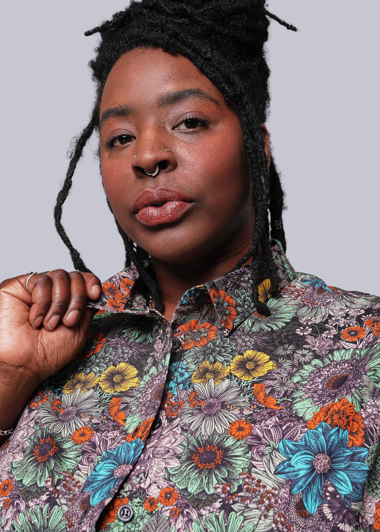 1X=Person wearing a colorful floral patterned shirt against a plain background