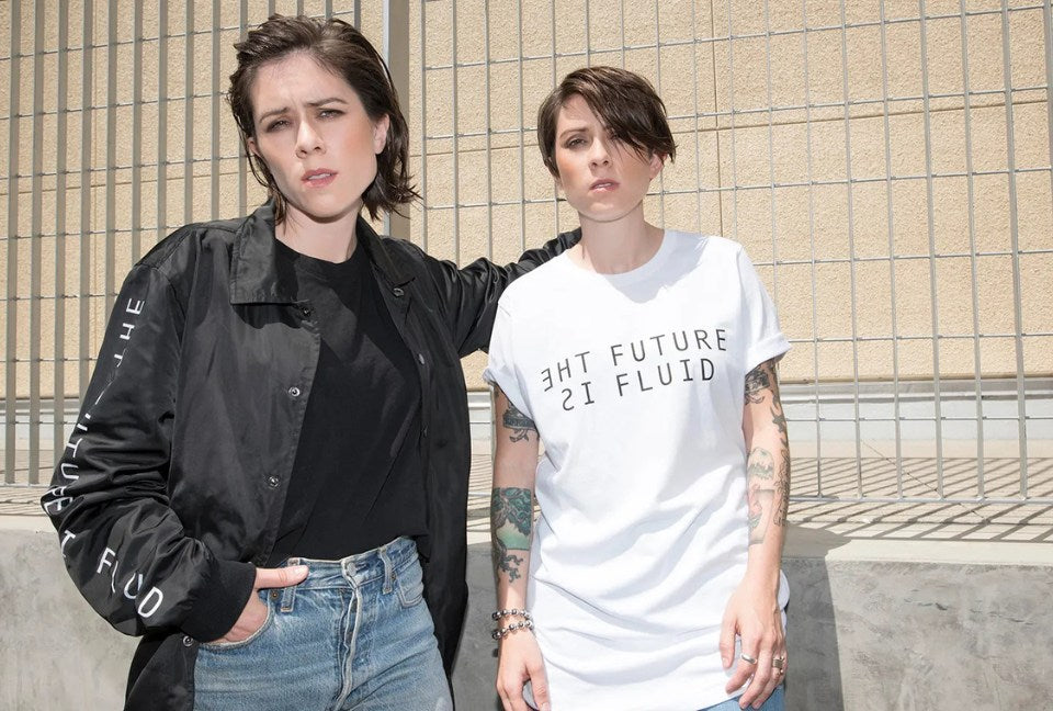 Tegan and Sara, the band members, pose for camera wearing pieces from their collection that say "The Future is Fluid" on them.