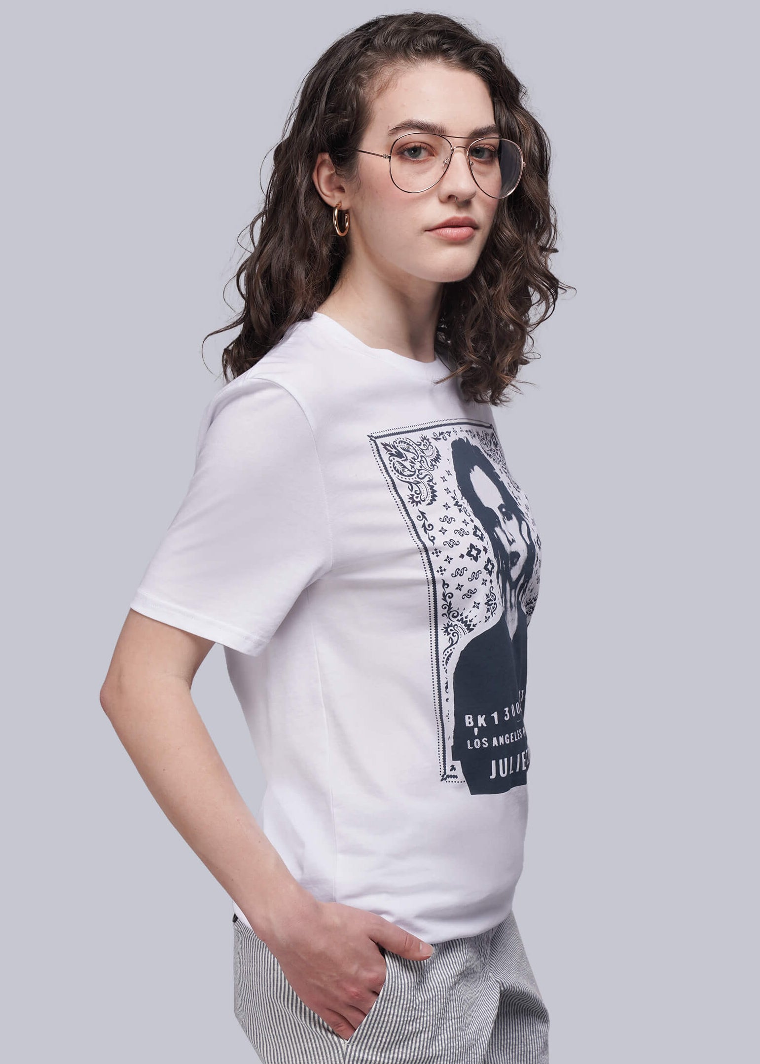 S=Woman wearing a white t-shirt with a graphic design on a plain background