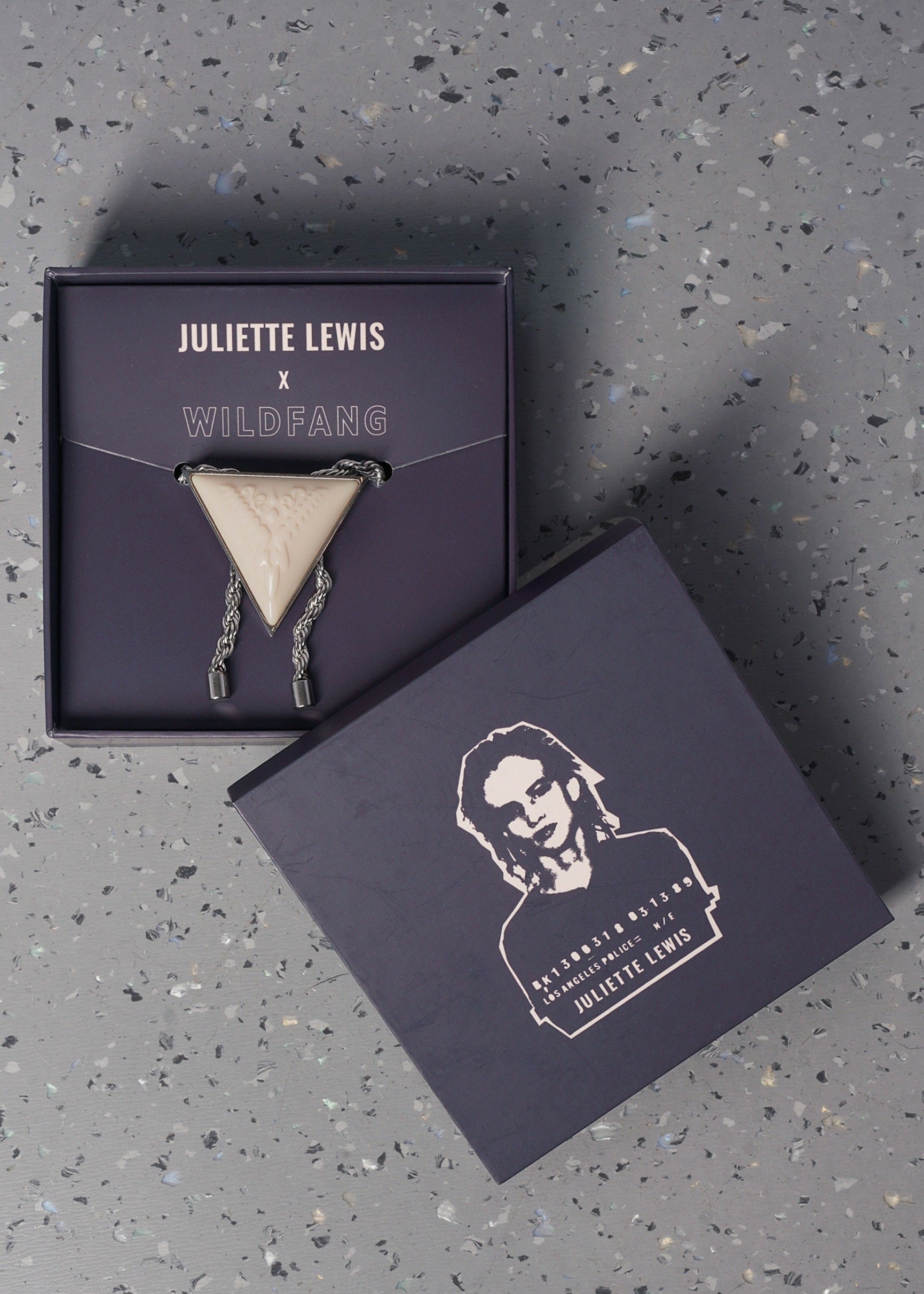 Juliette Lewis x Wildfang bolo tie in a branded box on a gray speckled surface