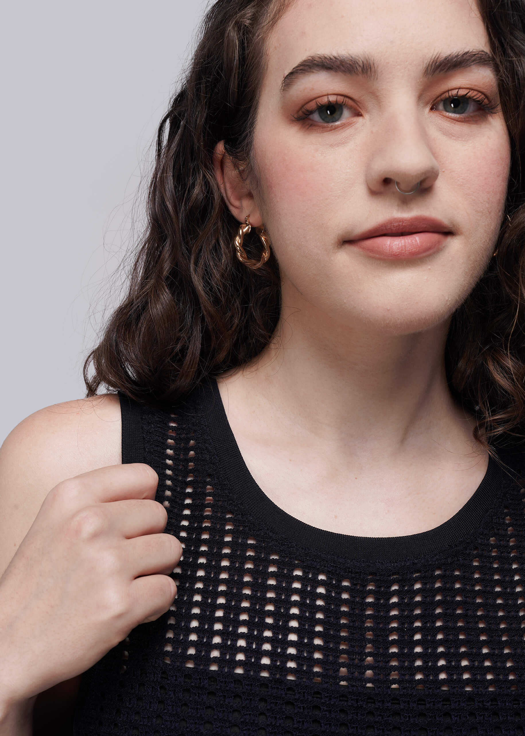S=Woman wearing a navy blue knit mesh sleeveless top against a plain background