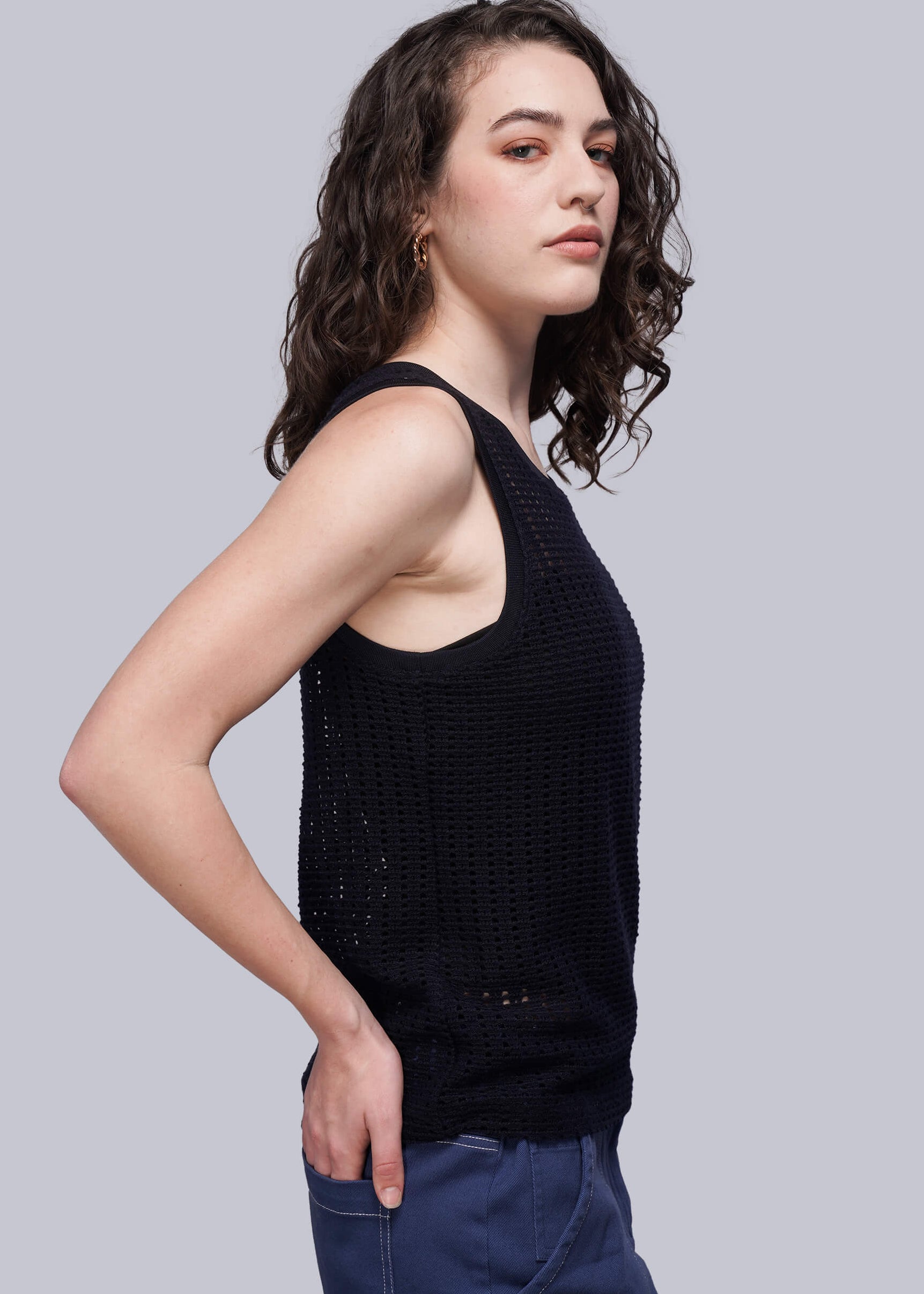 S=Woman wearing a navy blue knit mesh sleeveless top against a gray background