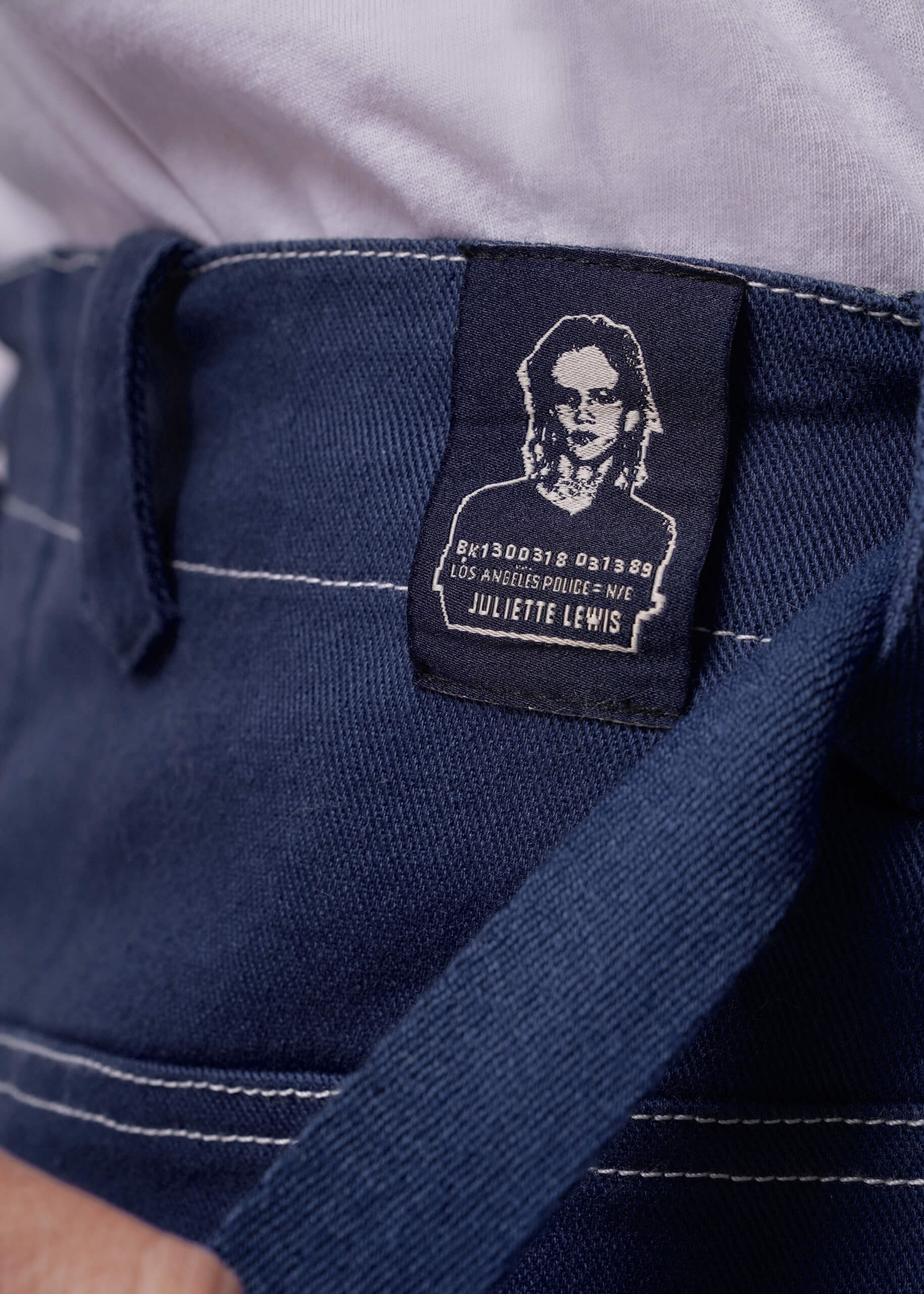 S=Close-up of a navy blue pant waistband with a label featuring a portrait and text.