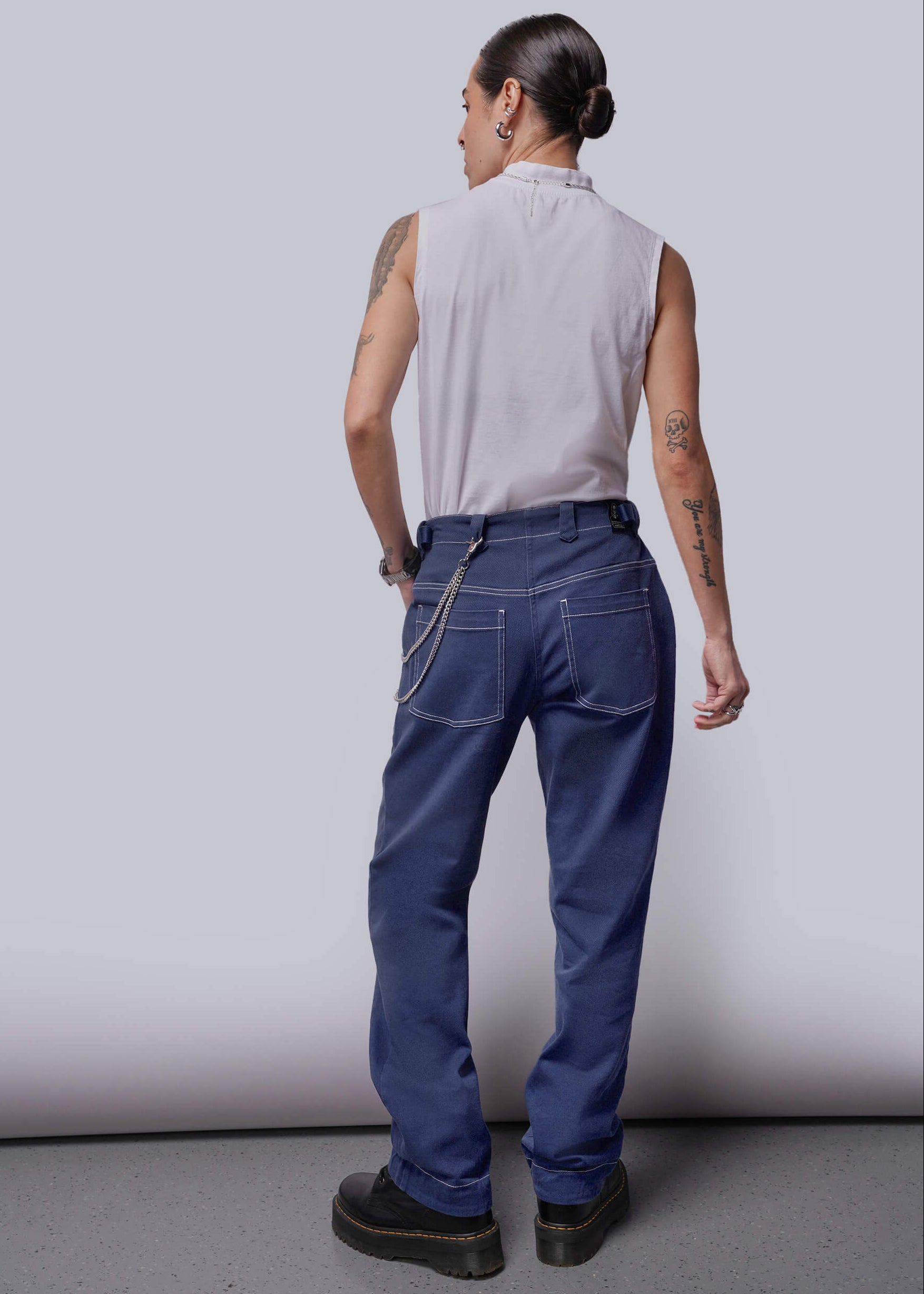 S=Person wearing a sleeveless shirt and blue pants against a plain background