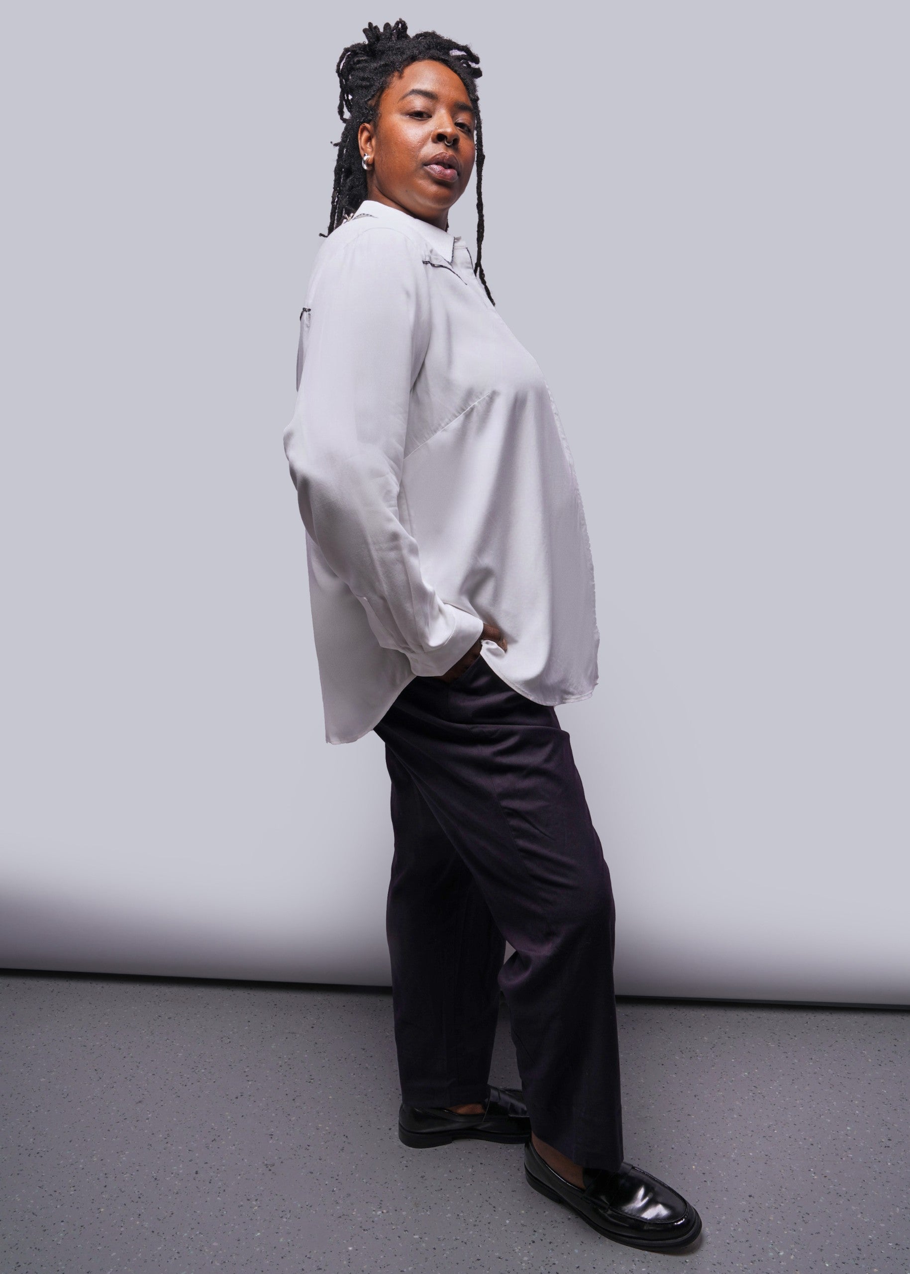 1X=Person wearing a white button up shirt and black pants against a plain background