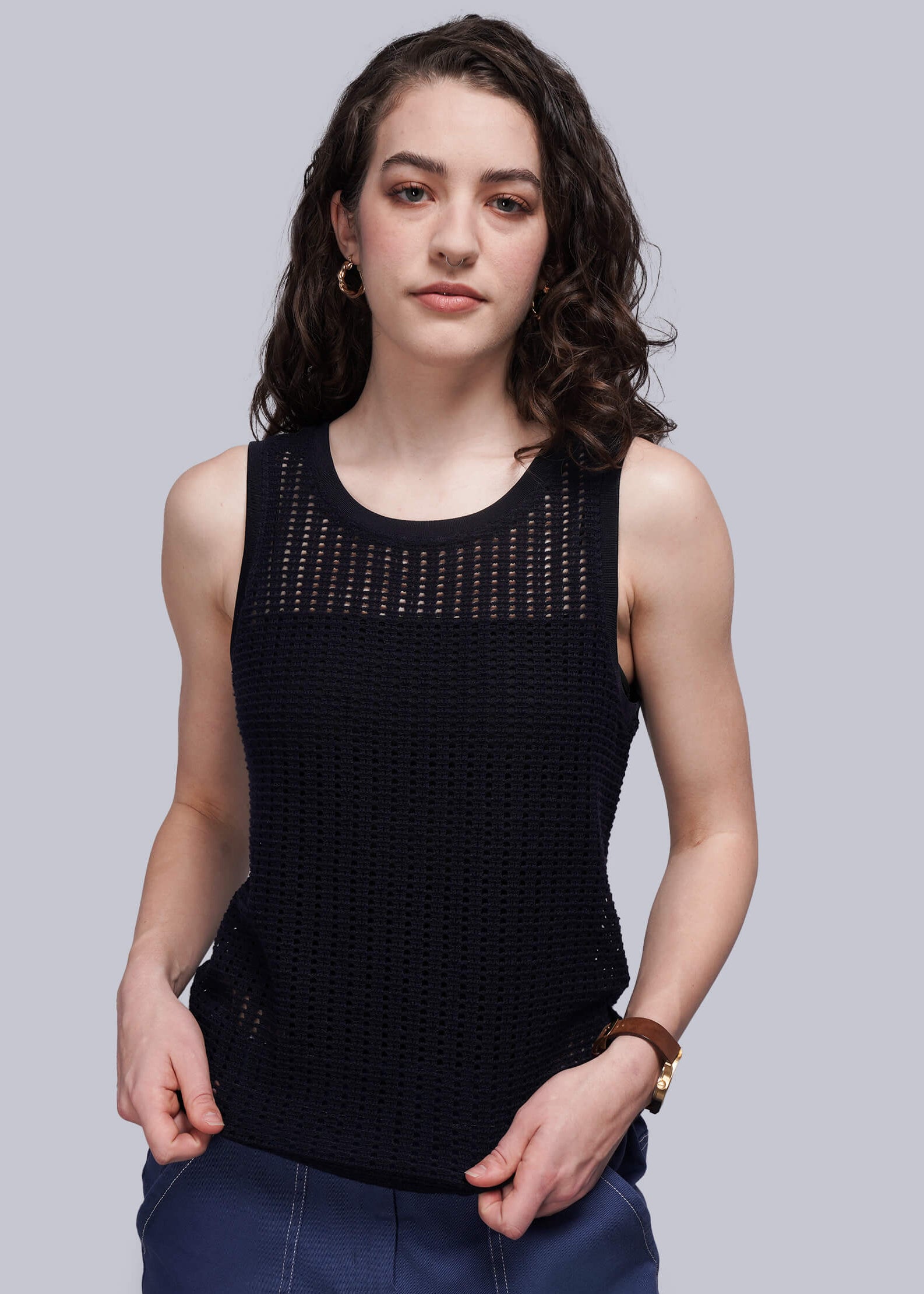Woman wearing a navy blue mesh sleeveless top against a gray background