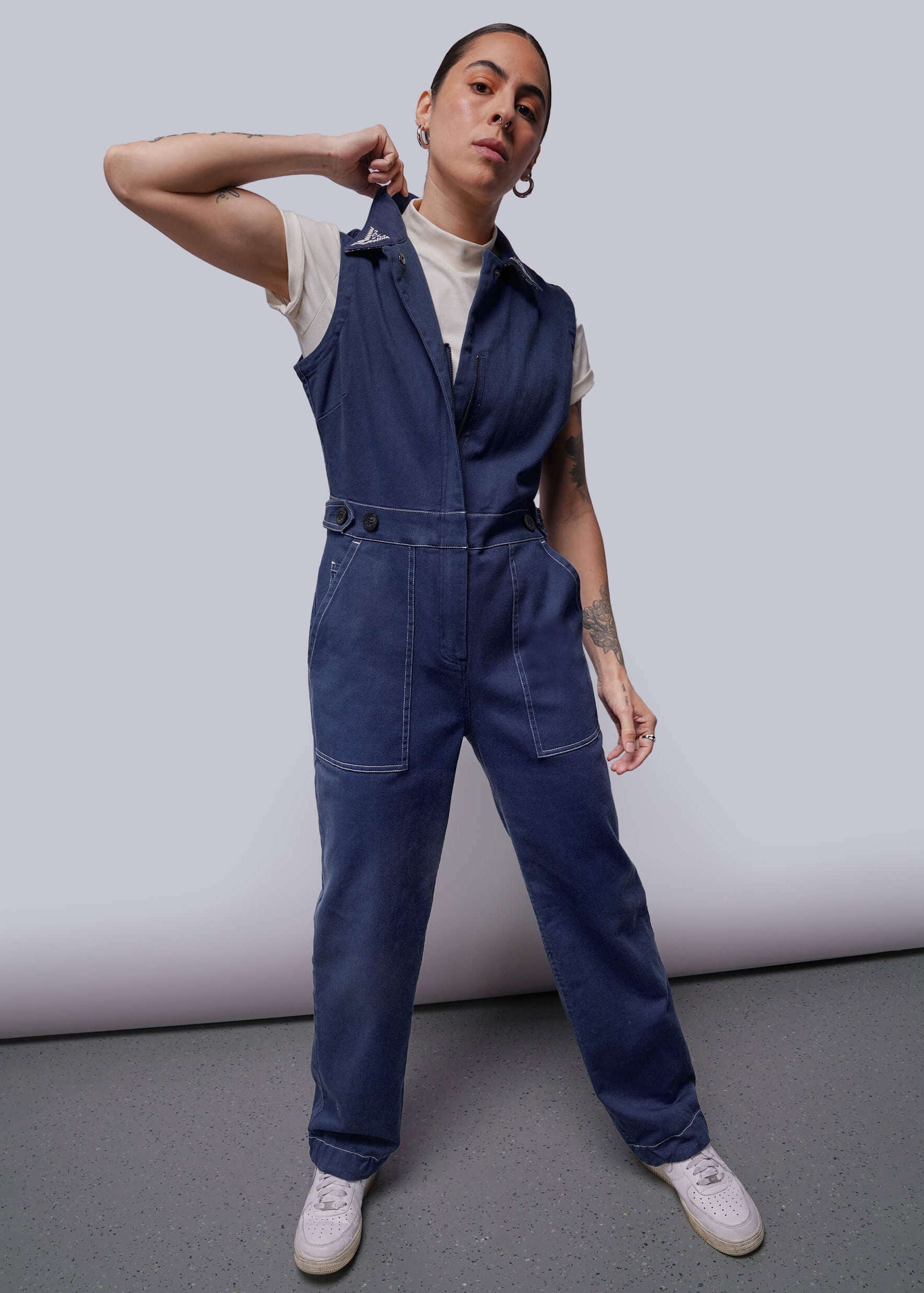 S=Person wearing a blue denim jumpsuit against a plain background