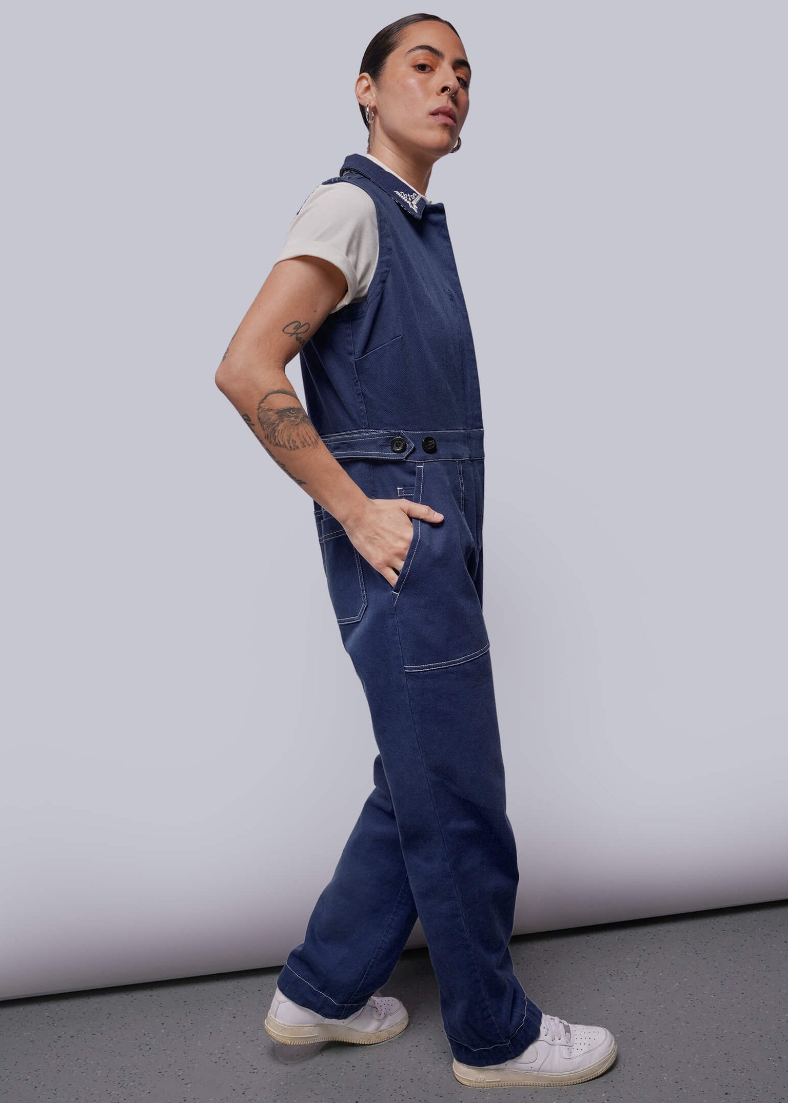 S=Person wearing blue sleeveless coveralls against a plain background