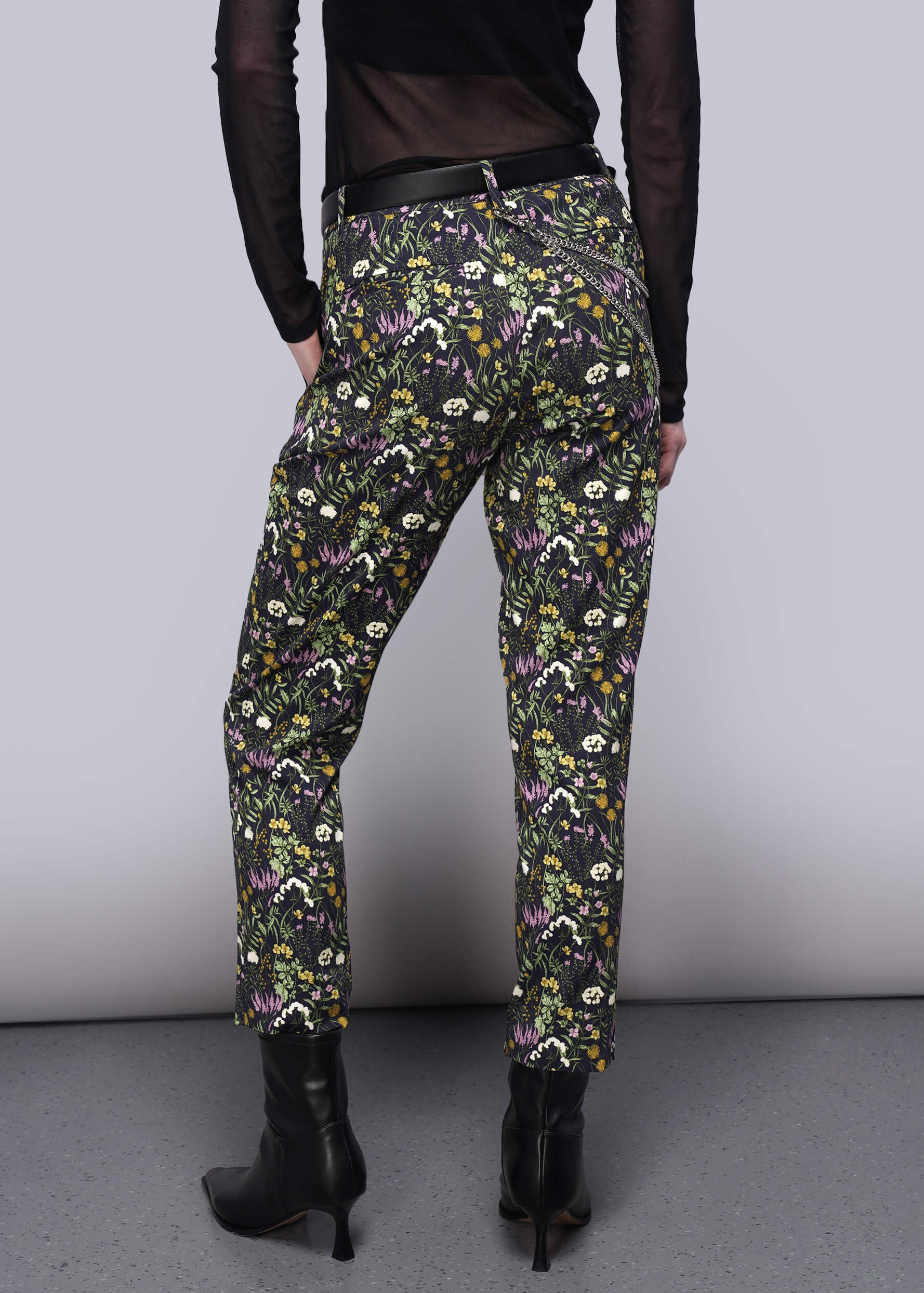 S=Person wearing floral patterned pants on a plain background