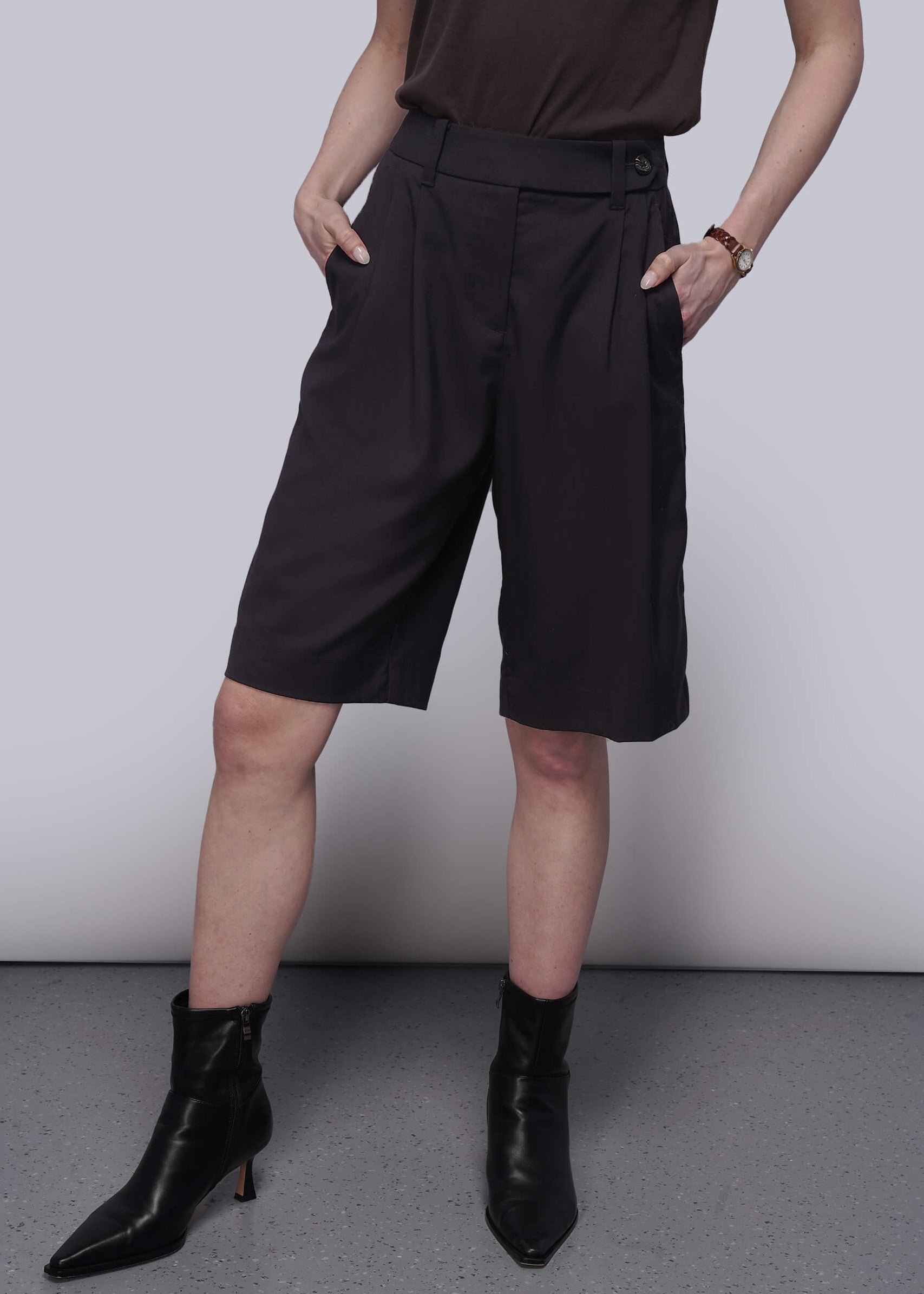 S=Person wearing black shorts and black boots against a plain background