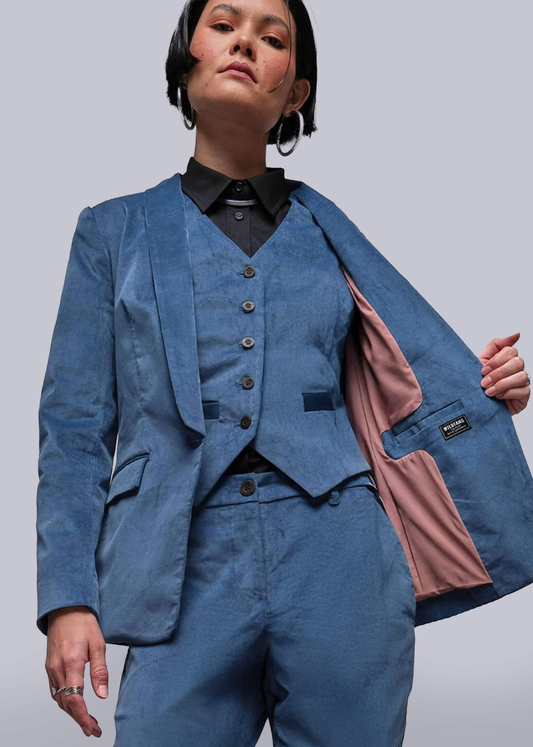 S=Person wearing a blue suit with a pink lining on a plain background