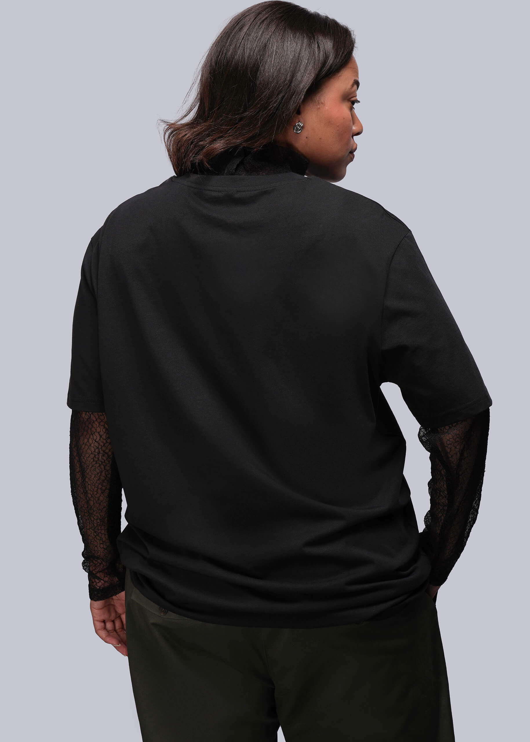 1X=Person wearing a black shirt with sheer sleeves on a gray background