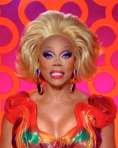 Person with bright makeup and colorful dress against a vibrant background