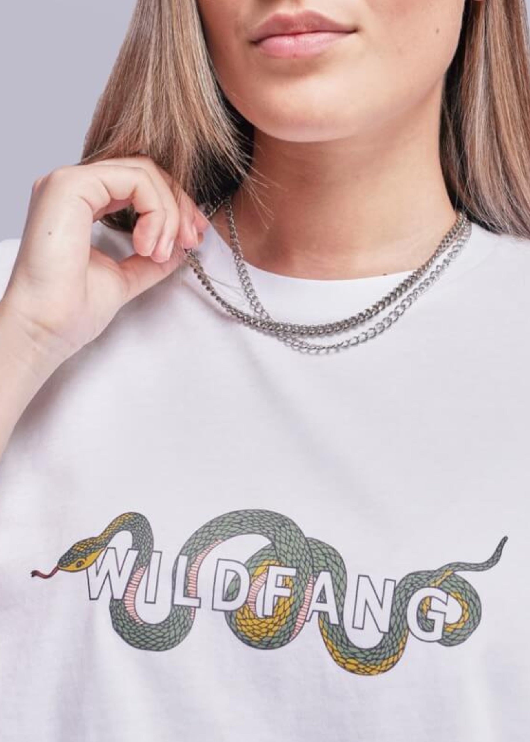Close up of model wearing white tee with Wildfang logo and snake design on it.