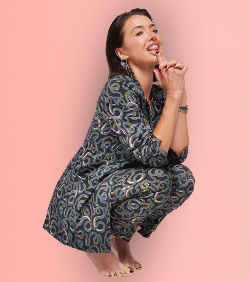 Parvati Shallow wearing serpentine suit against peach colored background